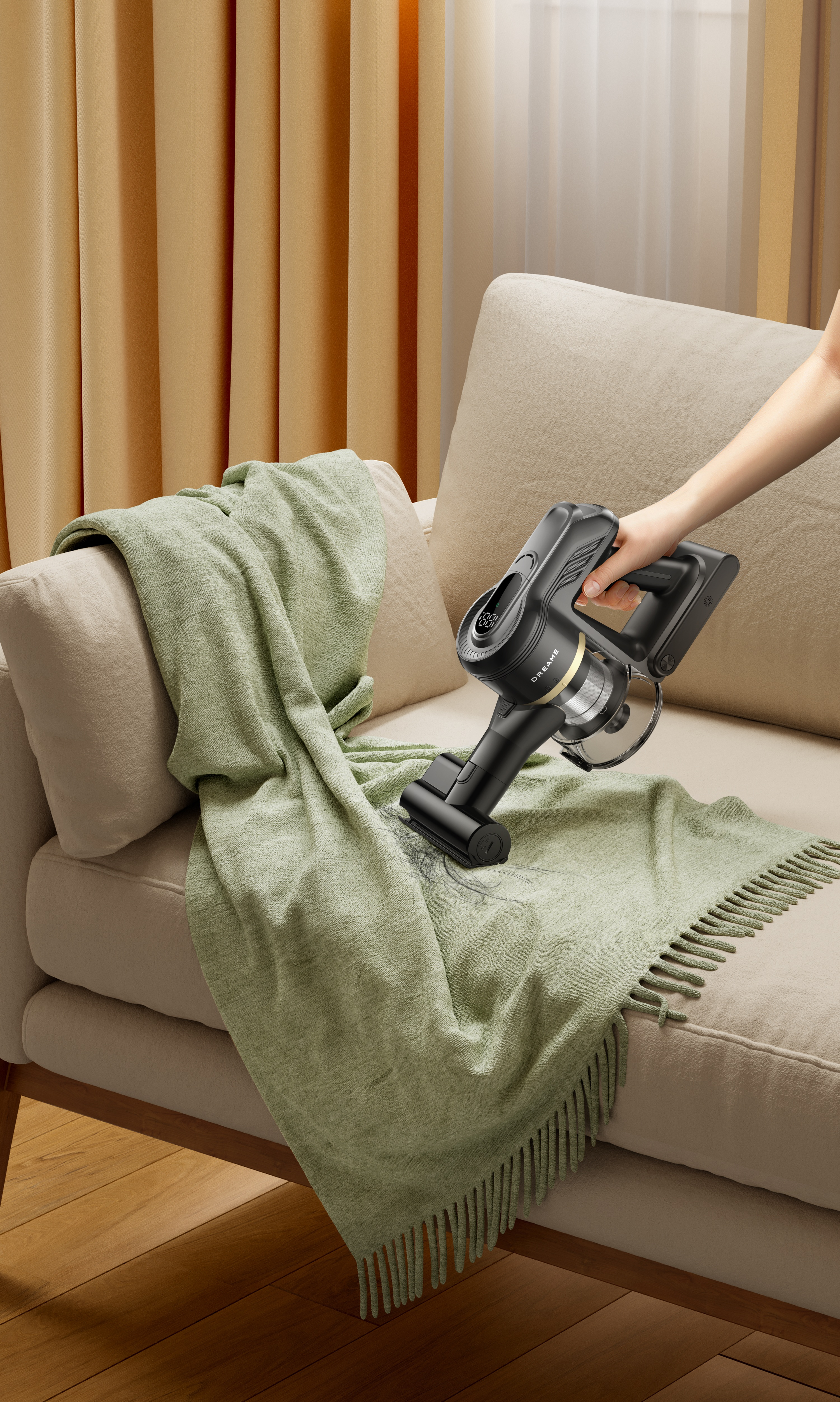 Osoba odkurza zielony koc na beżowej kanapie czarnym odkurzaczem bezprzewodowym. Beżowe zasłony w tle.