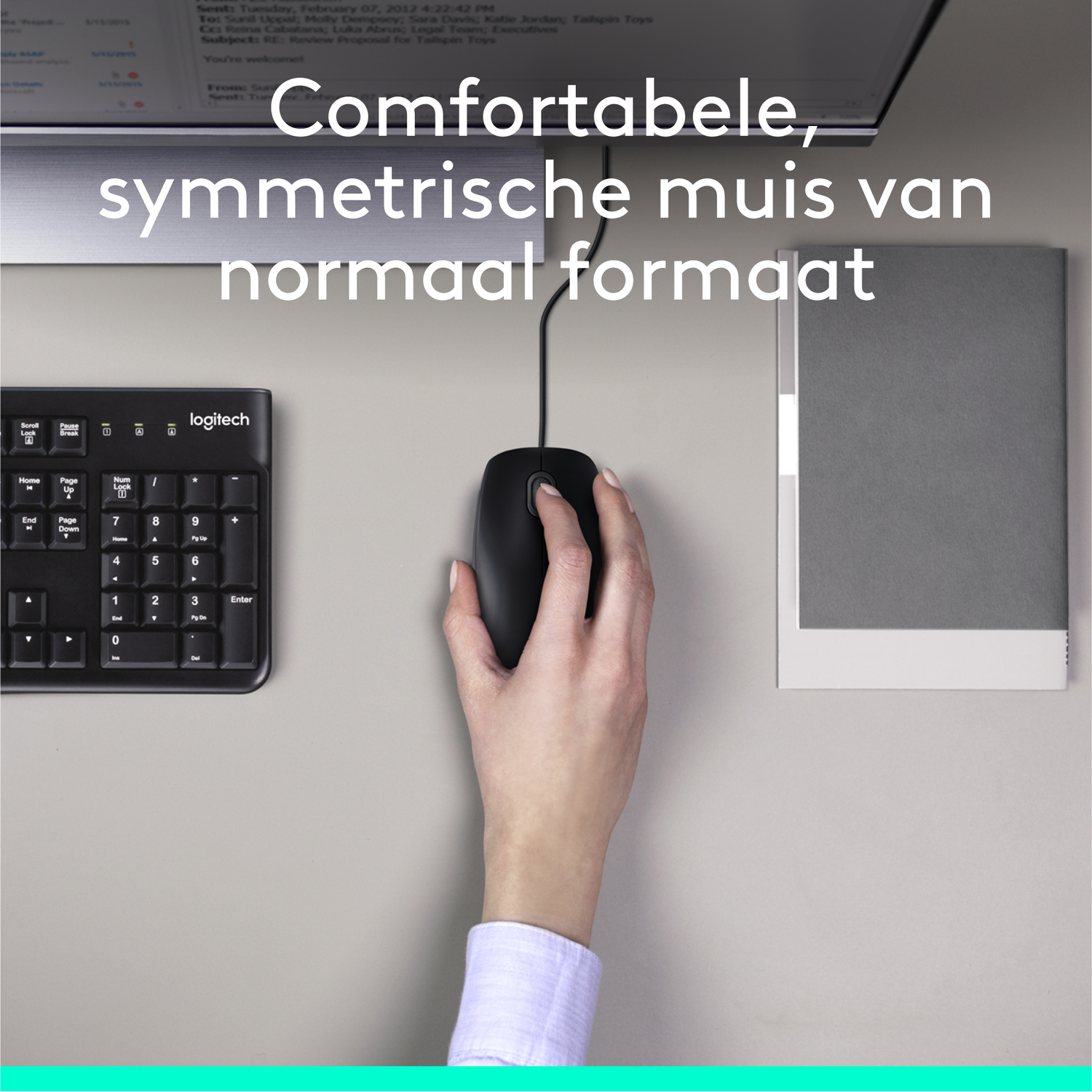 Een hand houdt een zwarte muis op een bureau, naast een toetsenbord en een grijze notitieblok. Tekst op het scherm is gedeeltelijk zichtbaar.