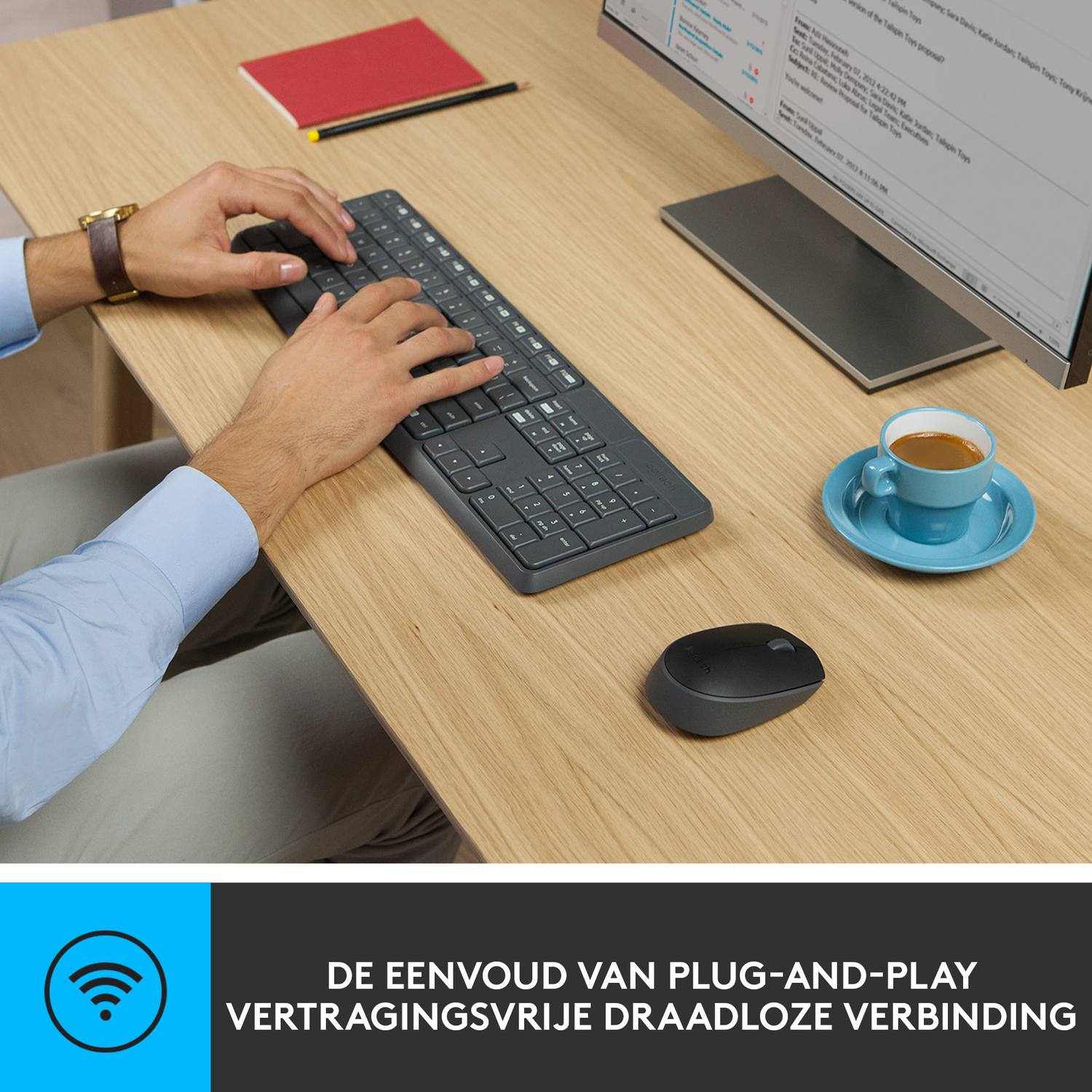 Een persoon typt op een grijs toetsenbord. Een muis en een kopje koffie staan op het houten bureau. Een monitor is zichtbaar.