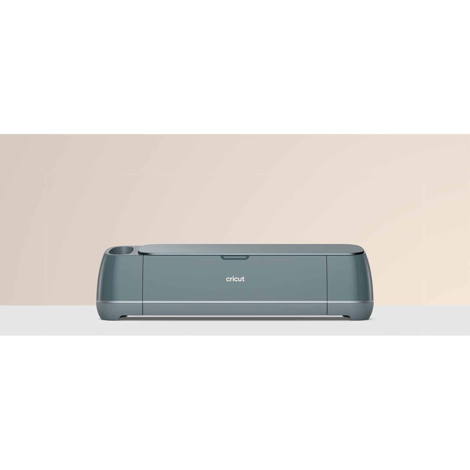 A teal Cricut machine on a white surface, with a light beige background. The brand name 'cricut' is visible on the machine.