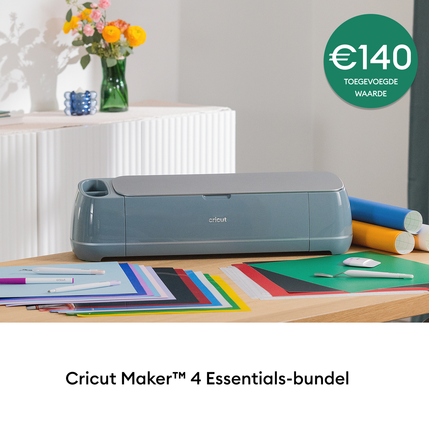 A Cricut machine with colorful paper and rolls, pens, and a green cutting mat. Flowers and a price tag are in the background.