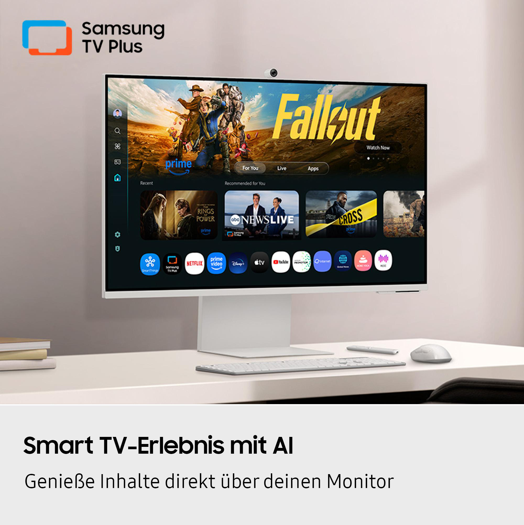 Ein Samsung TV Plus-Monitor zeigt die Show 'Fallout'. Apps, eine Tastatur und eine Maus befinden sich auf dem weißen Schreibtisch.