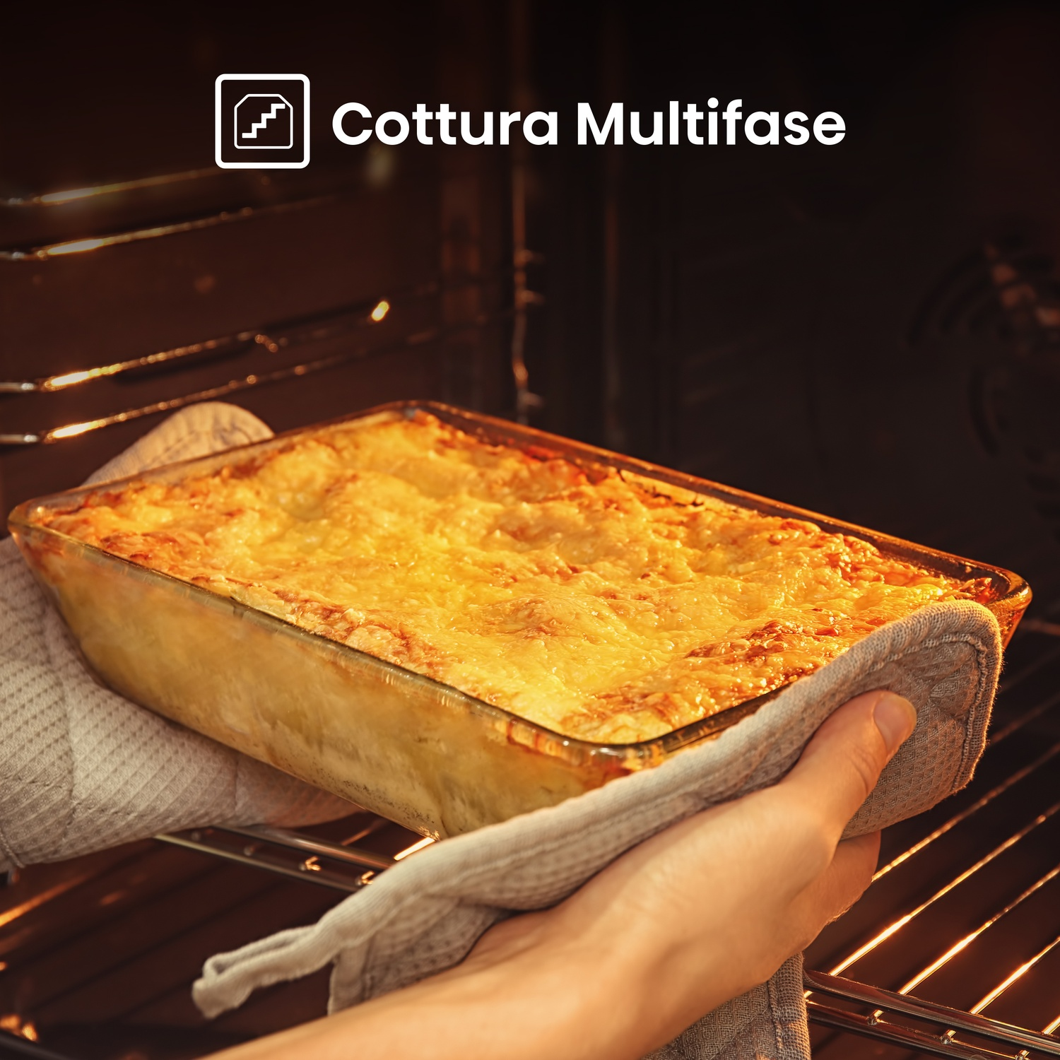 Una persona tiene una lasagna cotta in una pirofila di vetro, all'interno di un forno caldo. La parte superiore è dorata.