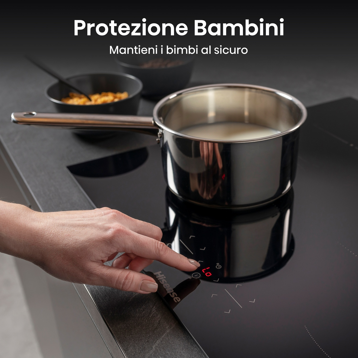 Una mano tocca un piano cottura nero. Una pentola di latte è sul fornello. Ci sono ciotole con cibo. Il testo recita: 'Protezione per bambini'.
