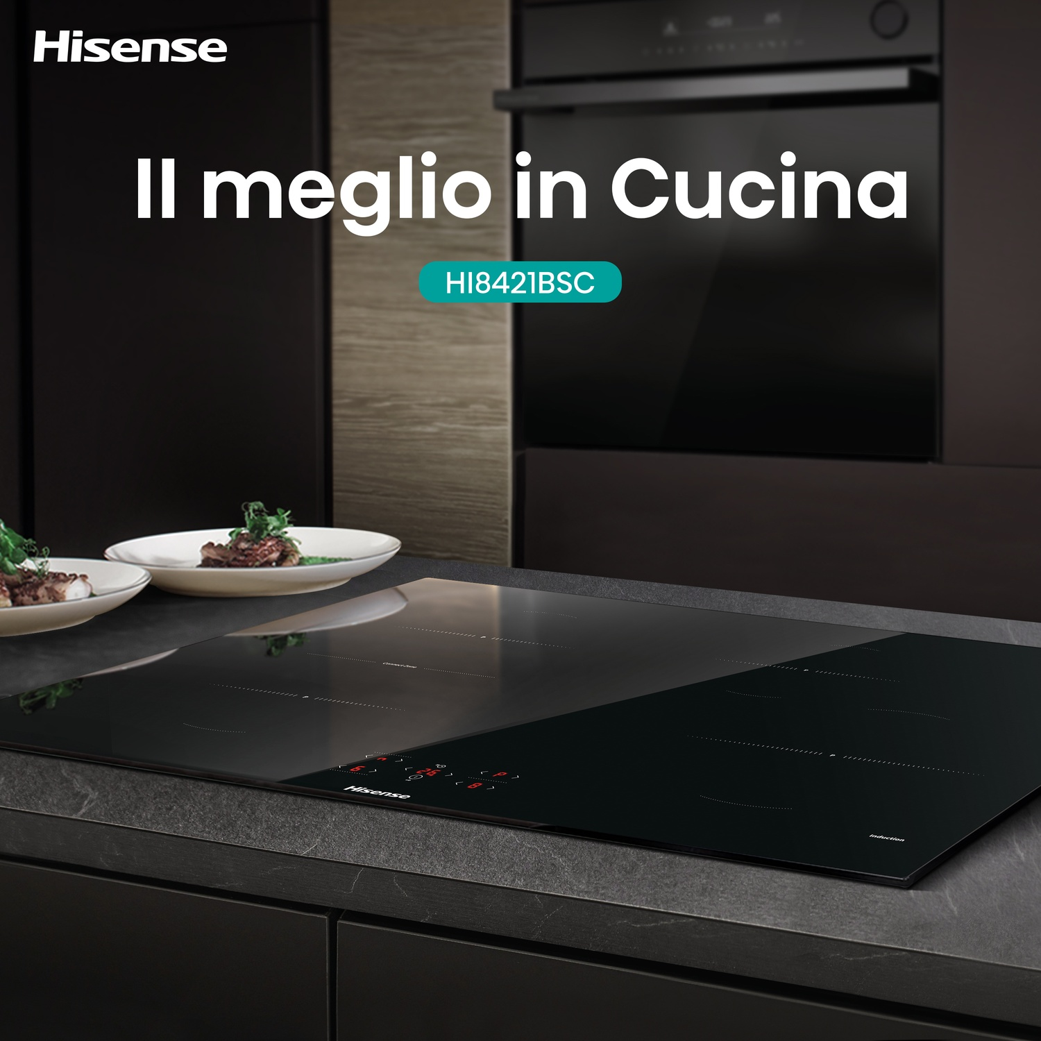 Una cucina moderna con un piano cottura nero, piatti di cibo e un forno a incasso. Il logo Hisense è in alto a sinistra.