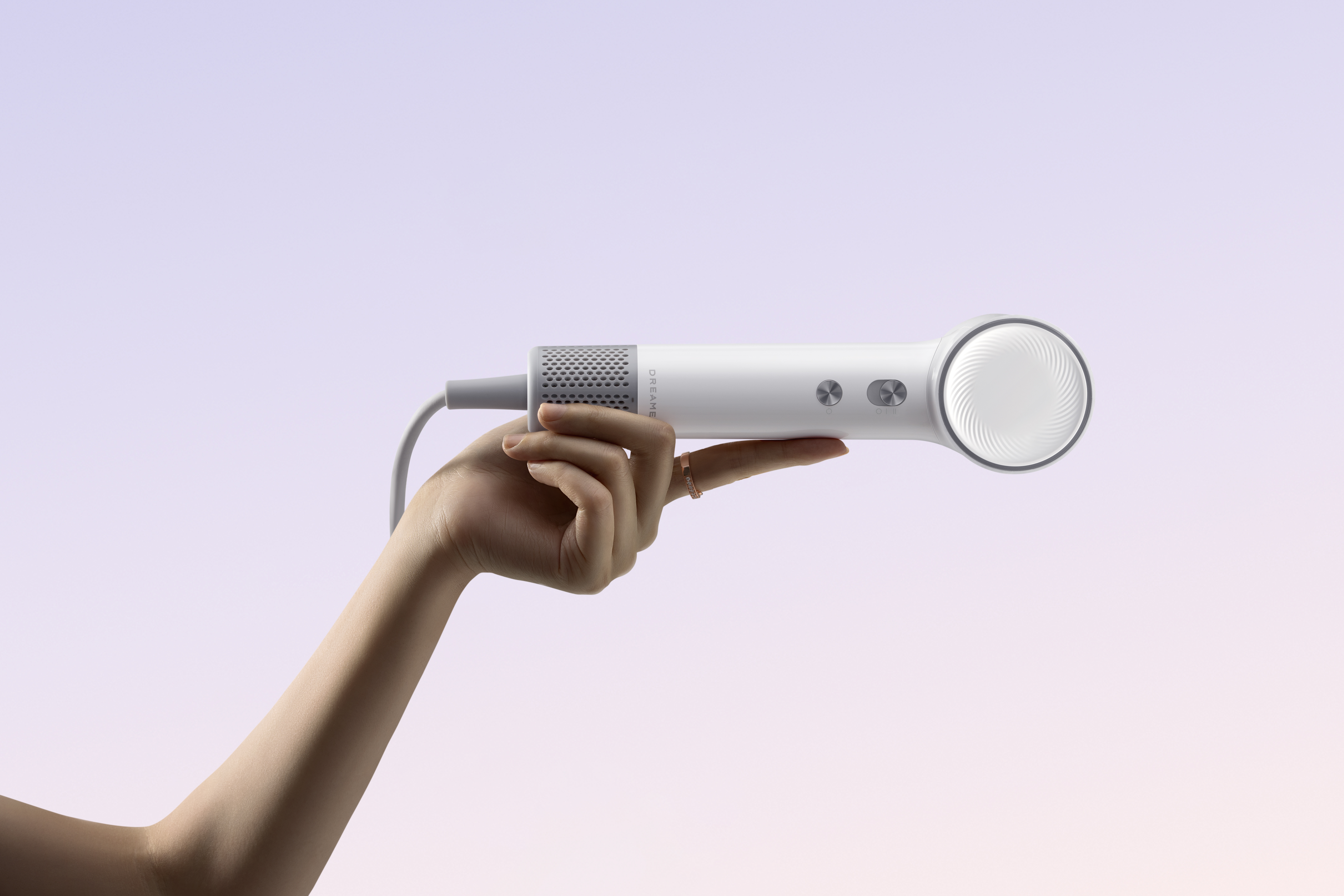 Dłoń trzyma białą suszarkę do włosów na tle gradientu. Suszarka ma szare akcenty i okrągłą głowicę.