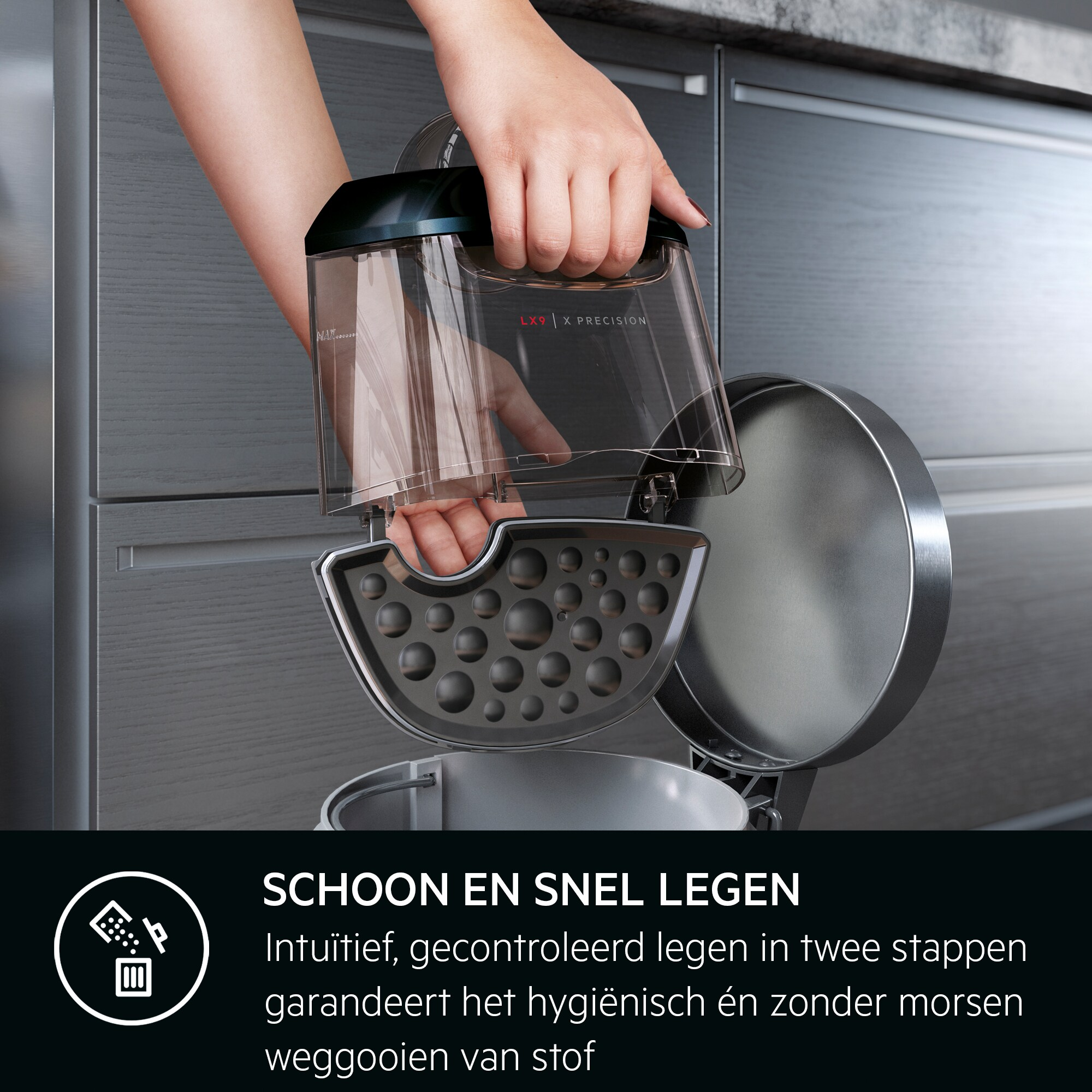 Une main tient un récipient transparent pour aspirateur au-dessus d'un réceptacle gris foncé. Le récipient est étiqueté LX9 X PRECISION.