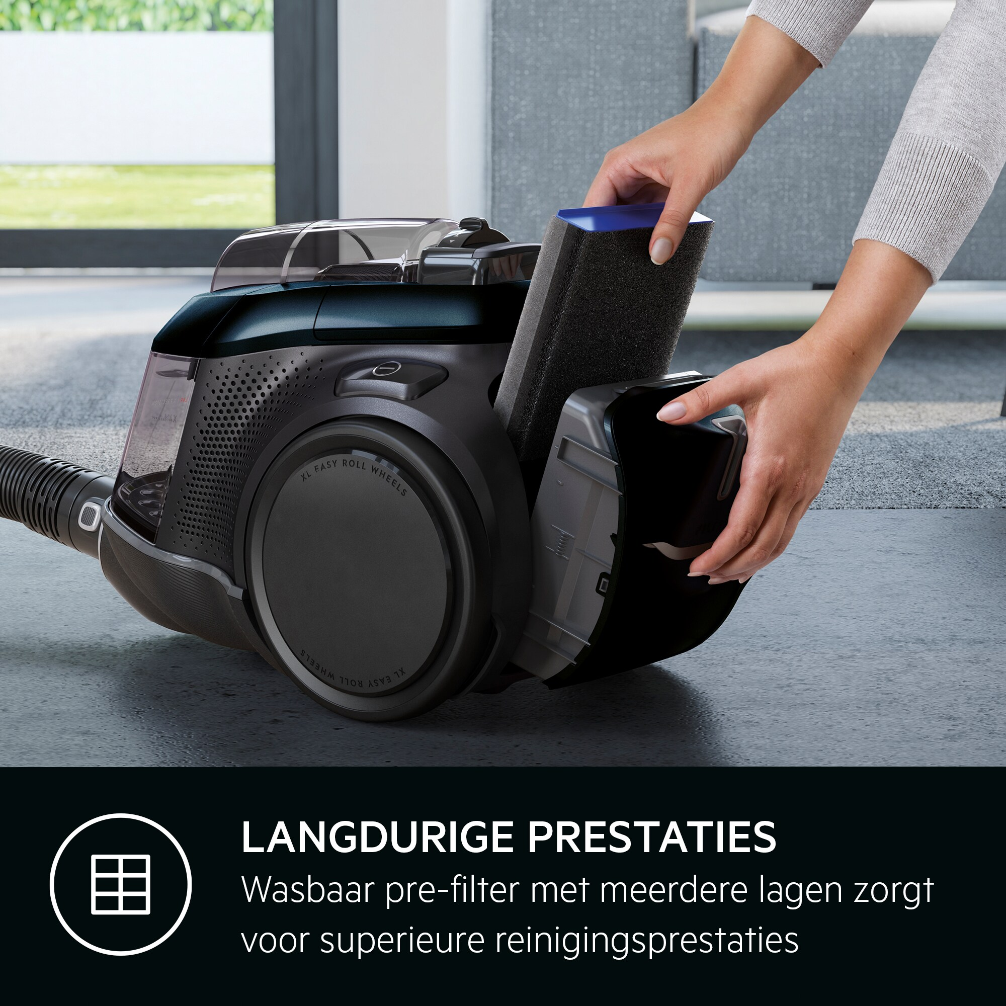 Des mains insèrent un filtre noir dans un aspirateur noir et transparent sur une surface grise.