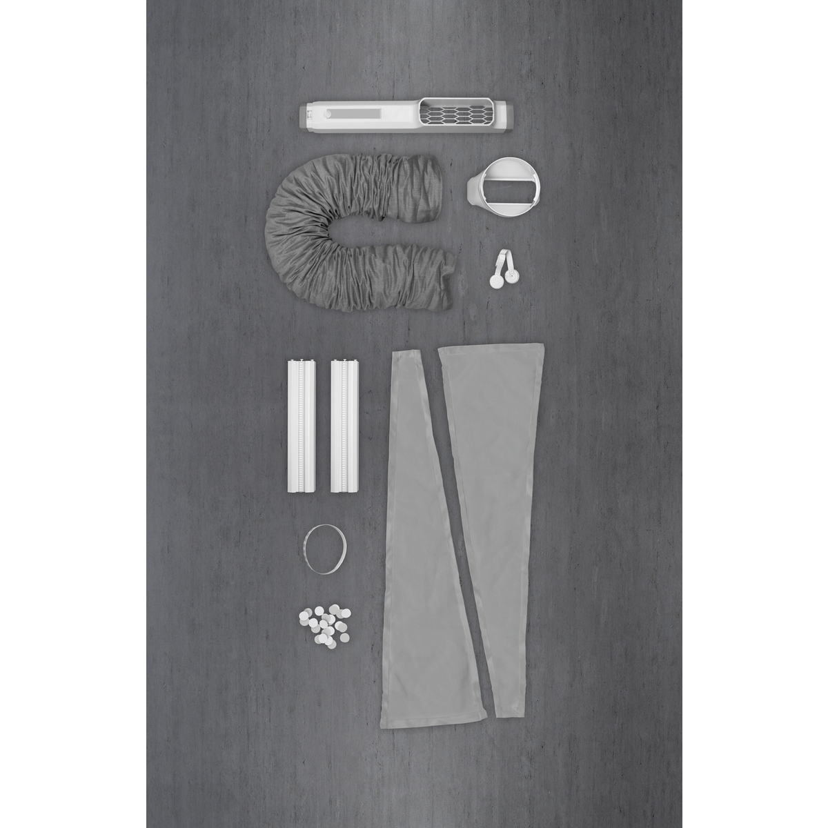 Arrangement of air conditioner components on gray surface. Includes the main unit, hose, connectors, and various other parts, all light gray.
