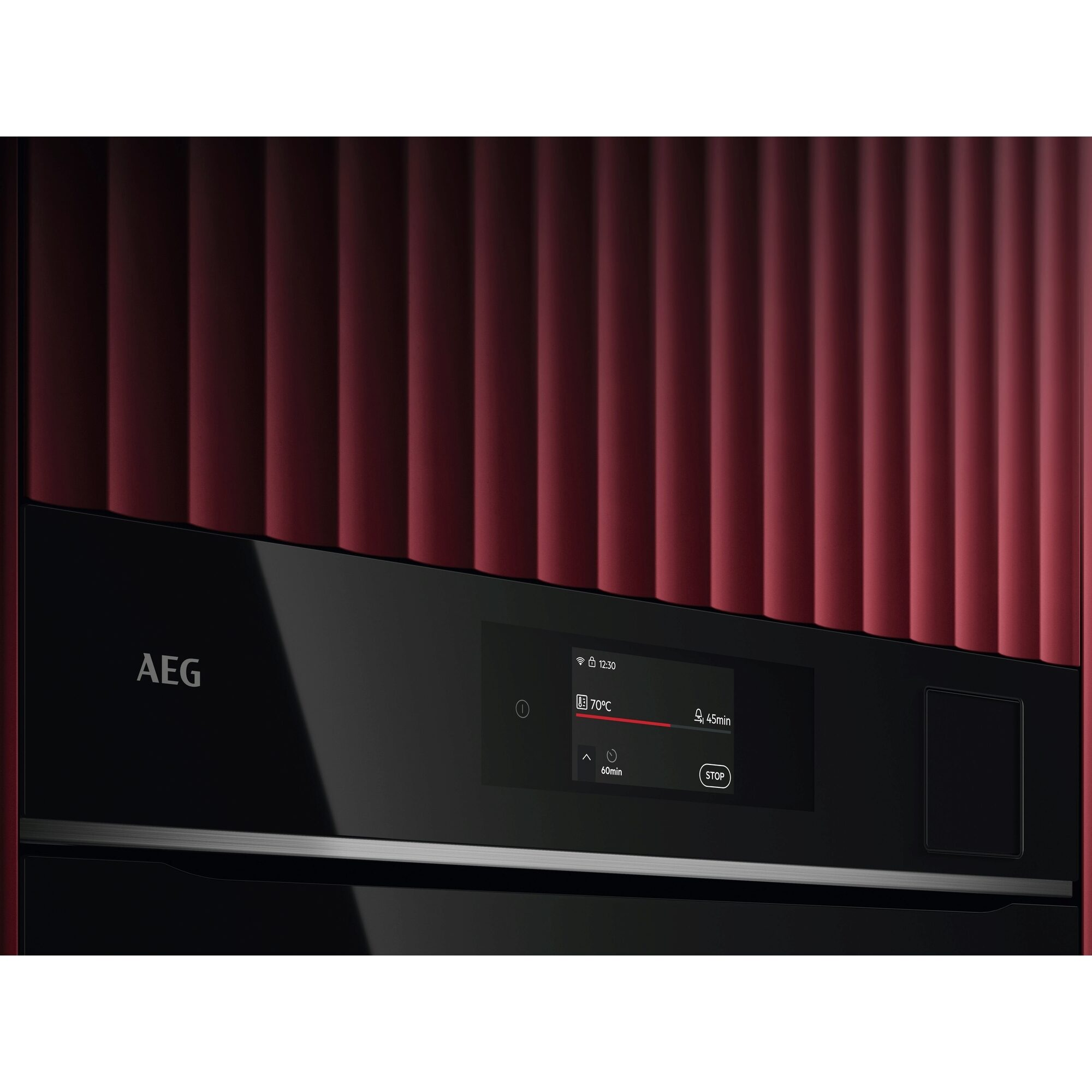 Ein AEG-Ofen mit schwarzer Blende und digitaler Anzeige. Der Hintergrund ist eine rote Platte mit vertikalen Linien.