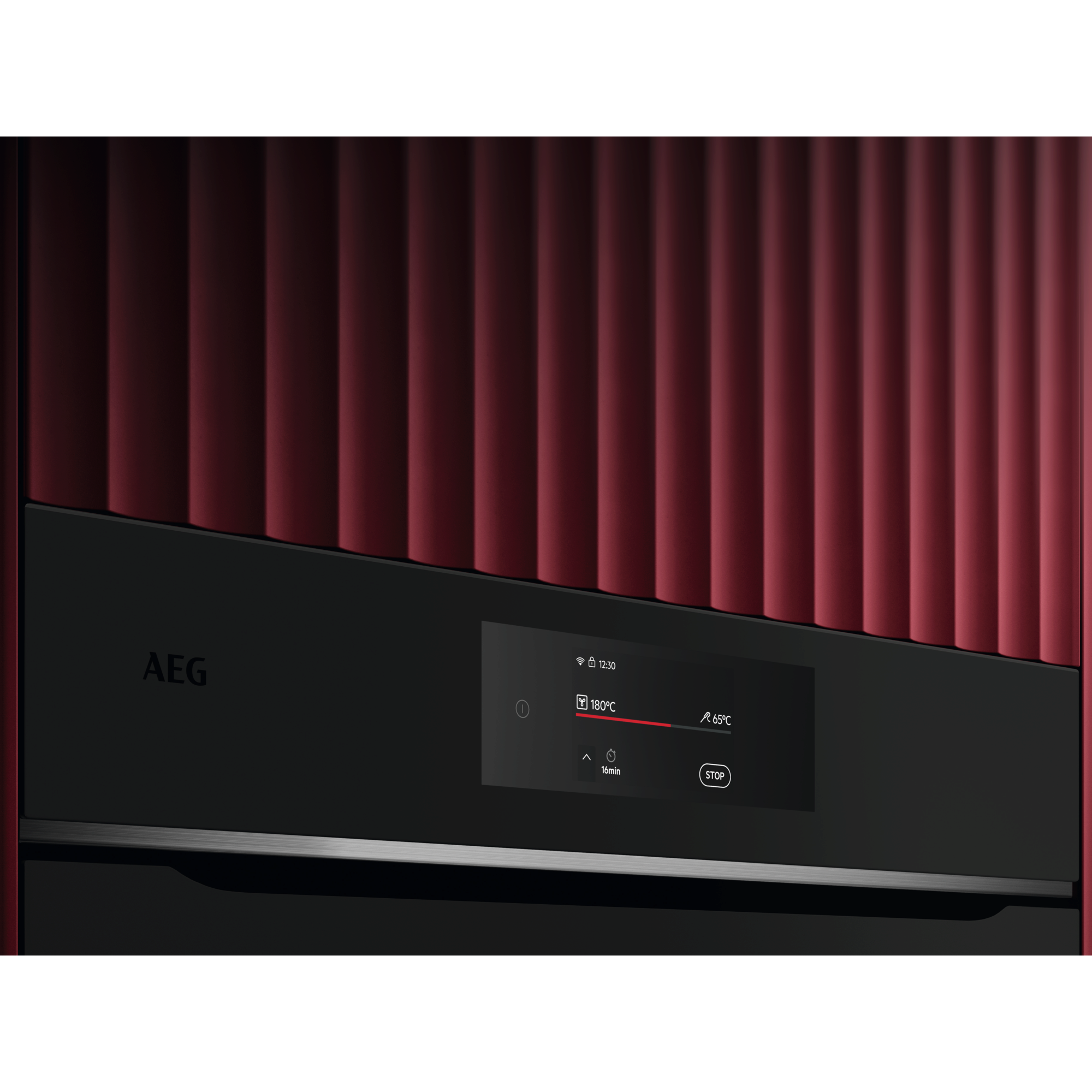 Nahaufnahme eines modernen Ofens mit Digitalanzeige. Rote Wellenpaneele im Hintergrund. Der Ofen ist schwarz mit AEG-Logo.