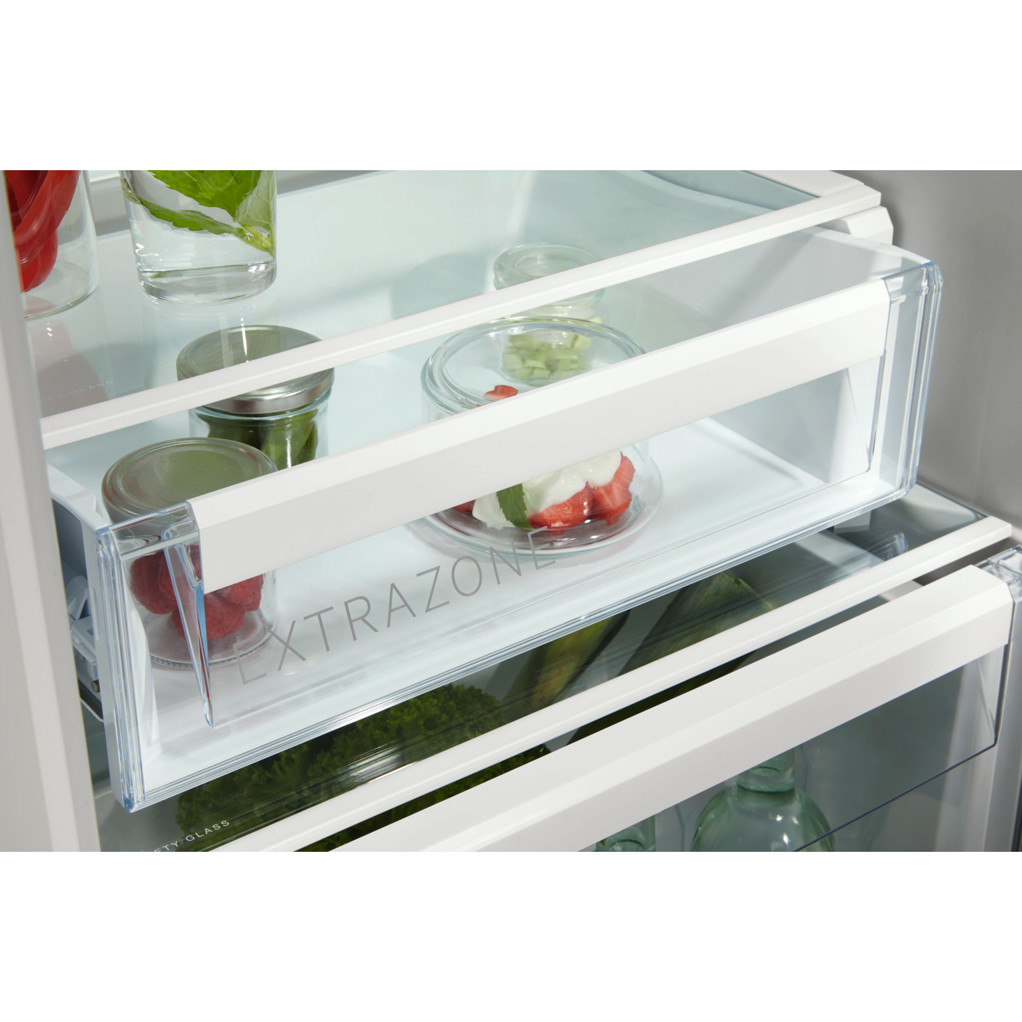 Kühlschrankinnenraum mit Glasböden und Schubladen. Enthält Obst, Gemüse und Kräuter in transparenten Behältern.
