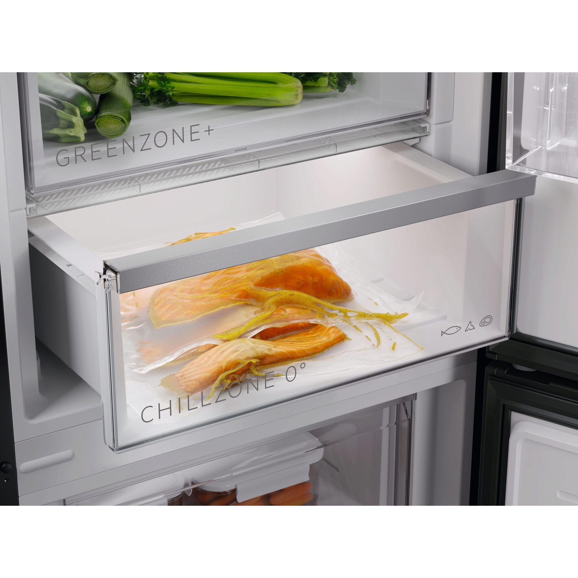 Im Kühlschrank liegen Lachsscheiben in einer Schublade mit der Aufschrift 'Chill Zone 0°'. Oben liegen Gemüse in der 'Green Zone+' Schublade.