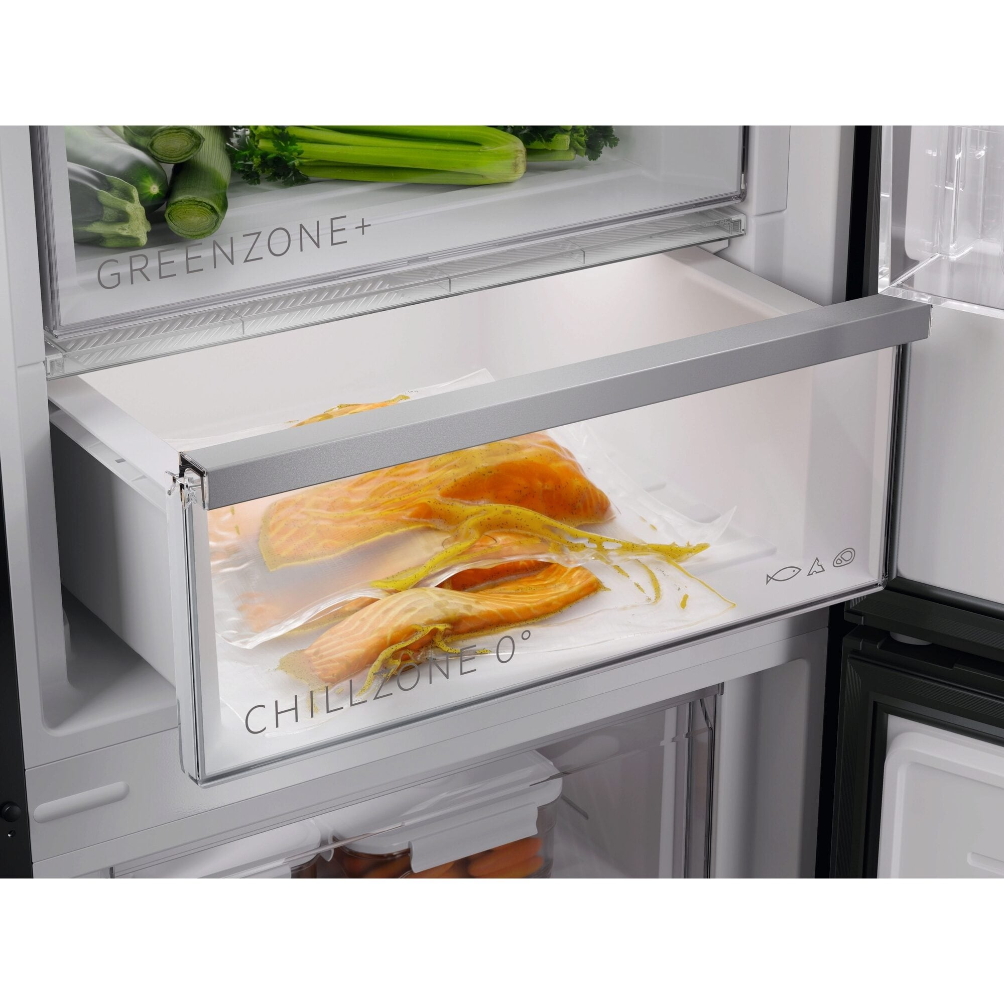 Kühlschrankinneres mit Lachs in einem durchsichtigen Plastikbeutel in einer Schublade und Gemüse in einer anderen Schublade darüber.