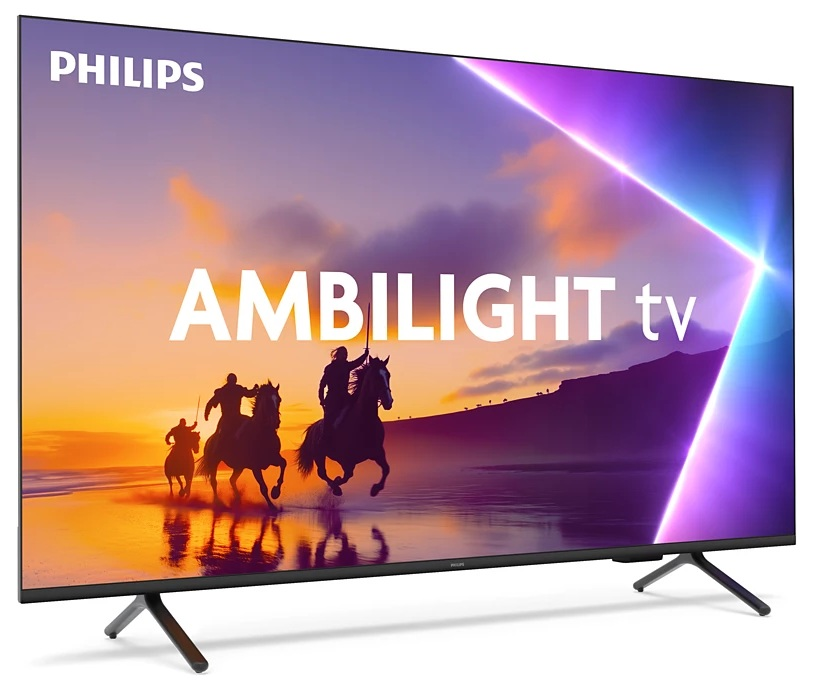 Telewizor Philips Ambilight pokazuje jeźdźców na koniach. Zachód słońca barwi tło. Ekran stoi na stojaku.