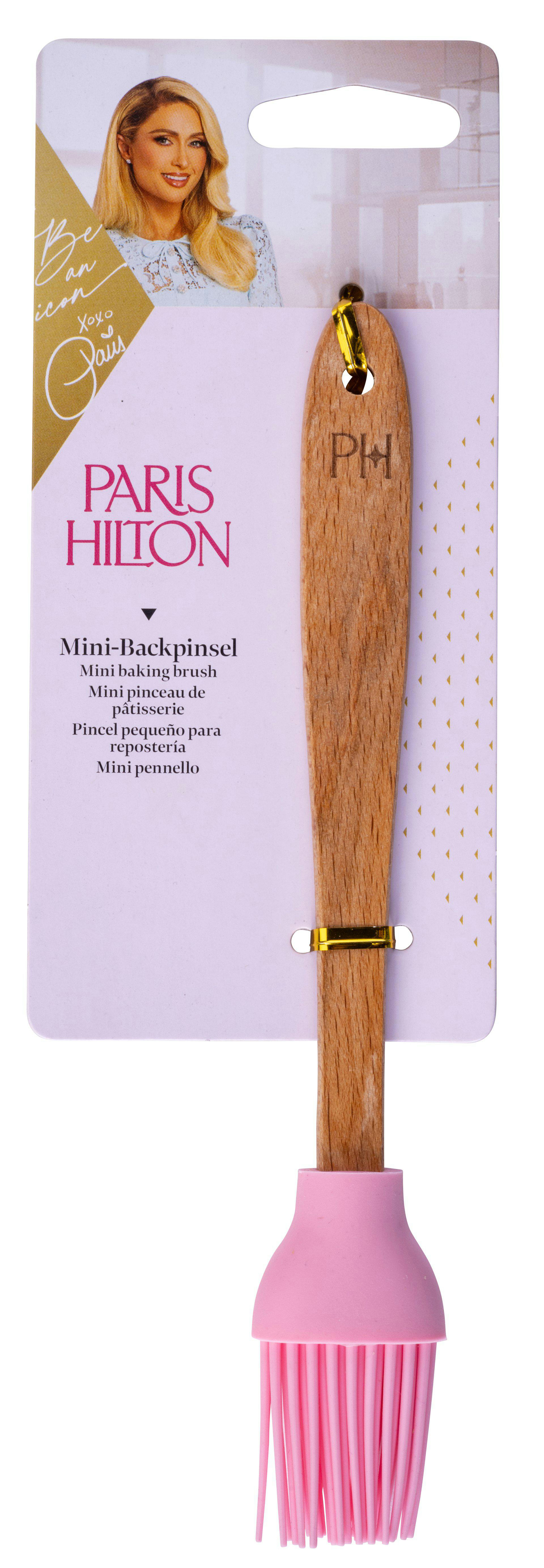 Ein Mini-Backpinsel der Marke Paris Hilton. Der Pinsel hat einen Holzgriff und einen rosa Silikonpinselkopf. Die Verpackung zeigt Paris' Bild.