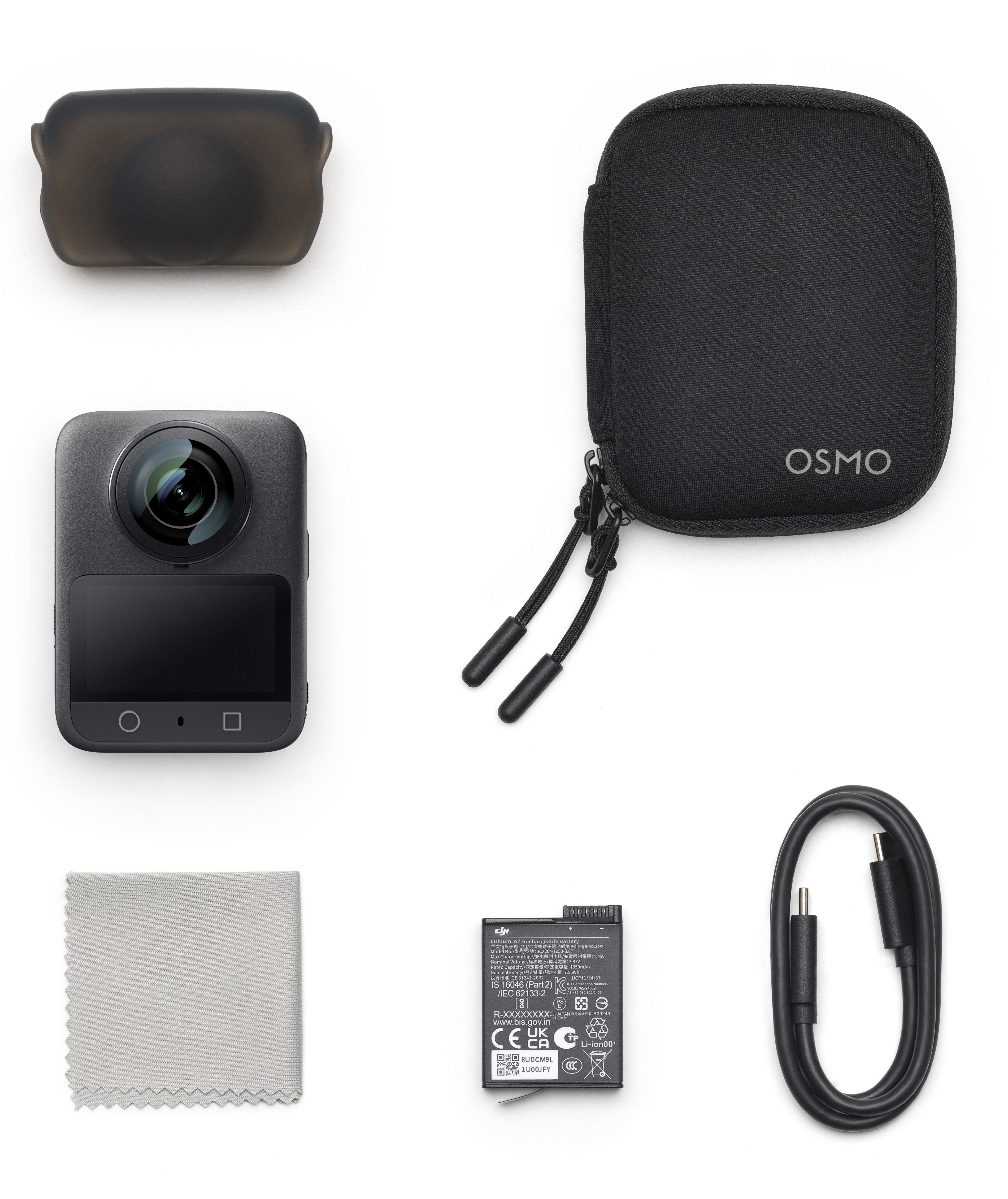 Czarny aparat, etui, kabel, bateria, osłona obiektywu i ściereczka. Białe tło.