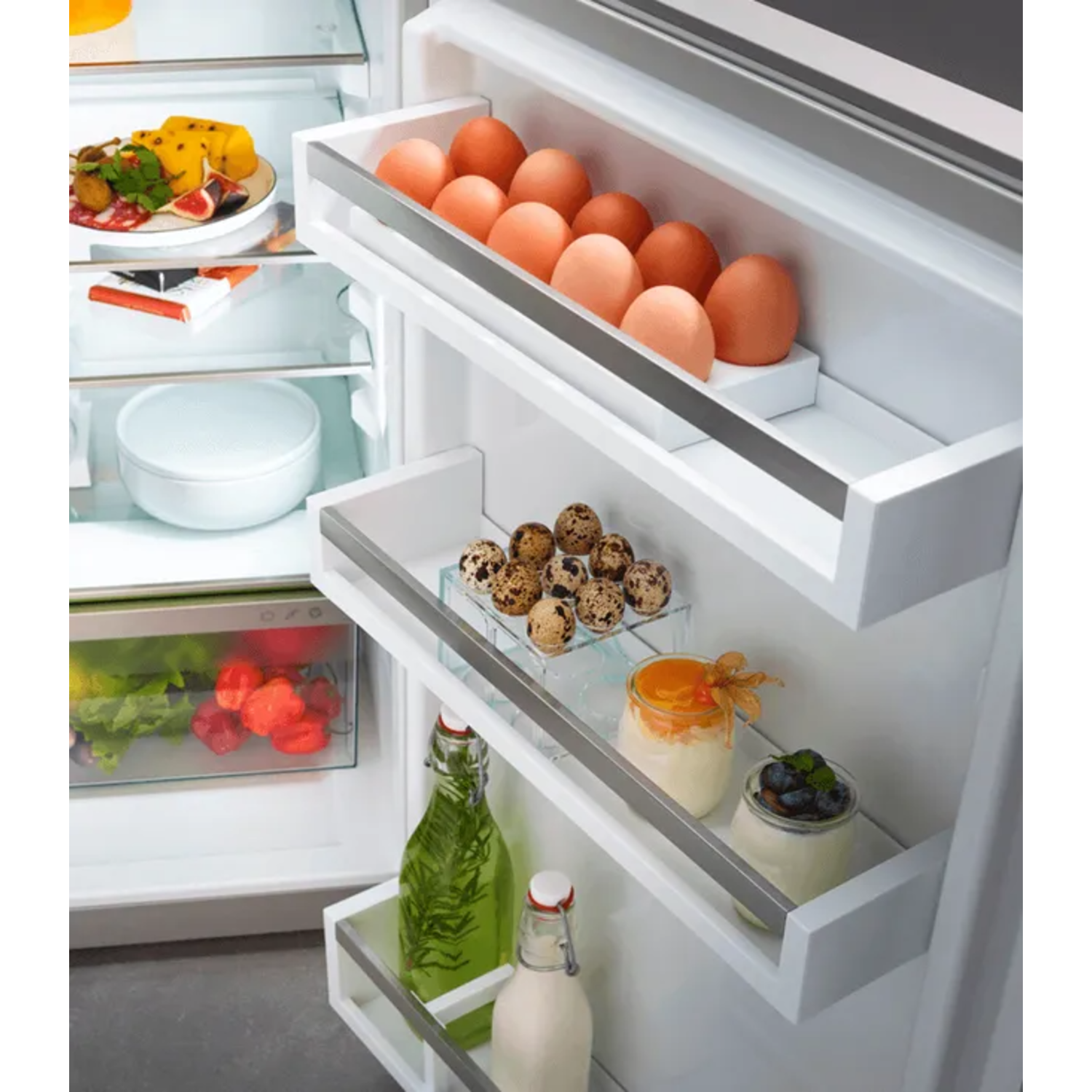Refrigerator with eggs, fruits, vegetables, and jars of food. Eggs are in a drawer. Jars have yogurt and berries.
