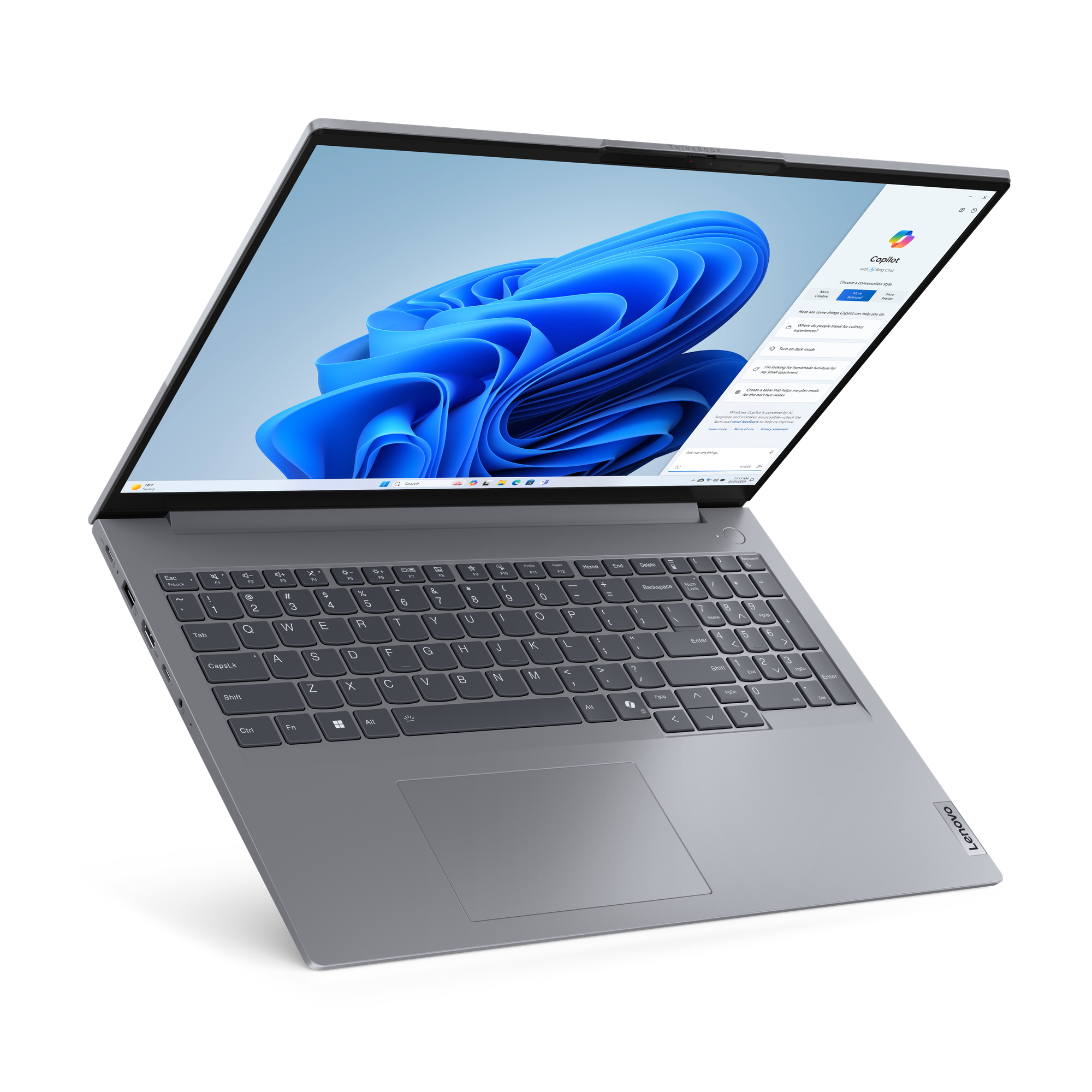 Szary laptop Lenovo, otwarty, wyświetlający interfejs Windows z niebieskim tłem i Copilot.