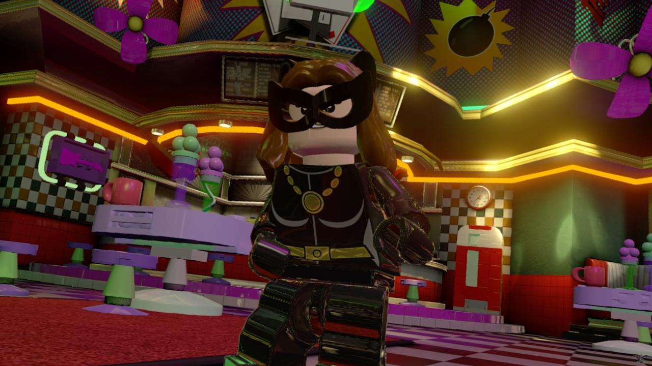 Kobieta-Kot Lego w barze. Nosi czarny kostium, maskę i brązowe włosy. Bar ma neonowe światła i lody.