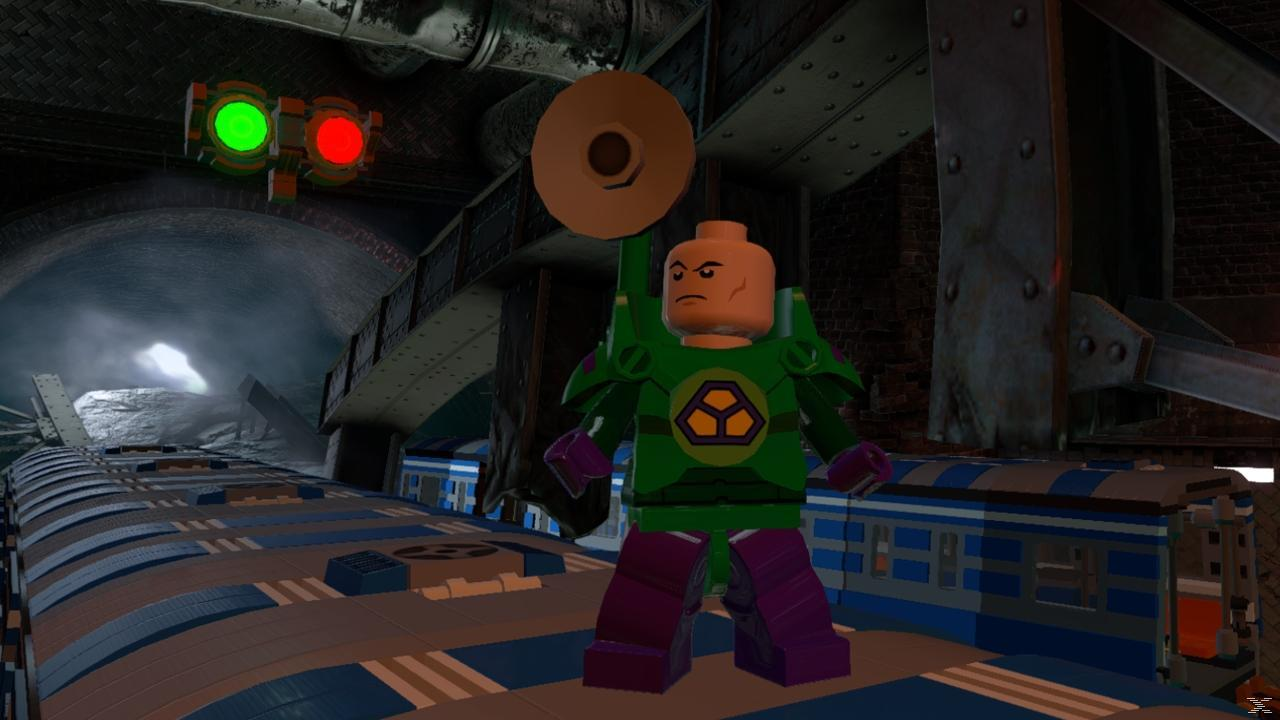 Lego Lex Luthor stoi na platformie z wagonami kolejowymi. Nad nim wisi sygnalizacja świetlna. Ciemny tunel w tle.