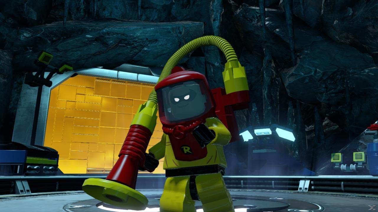 Figurka Lego w żółtym kombinezonie z czerwonymi akcentami, odkurzaczem i hełmem. Tło to skalna jaskinia.