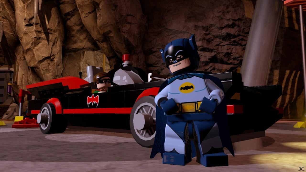 Lego Batman i Robin stoją obok Batmobila w jaskini. Batmobil jest czarny i czerwony. Tło pokazuje ściany jaskini.