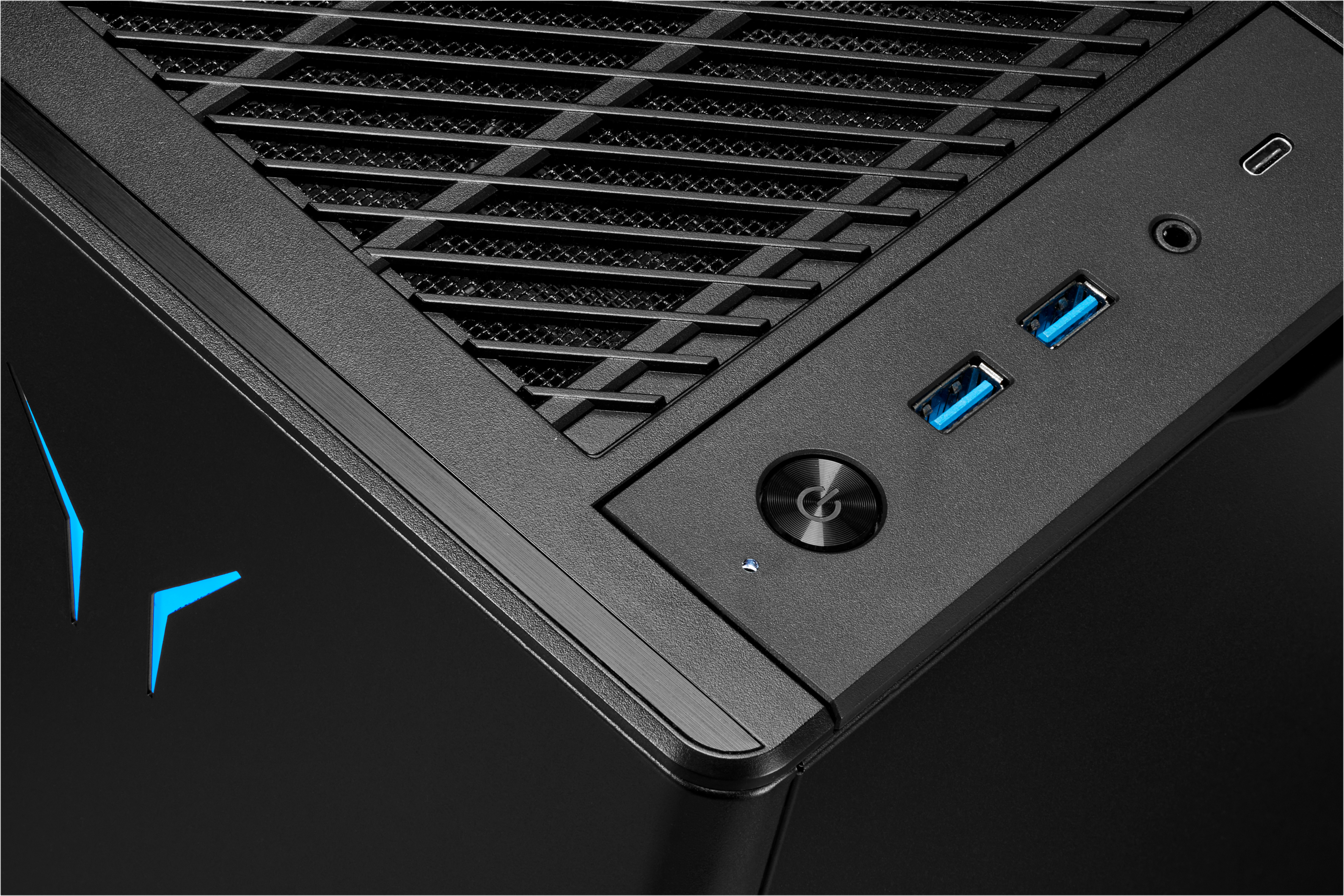 Schwarze Computerecke mit USB-Anschlüssen, Netzschalter und blauen LED-Akzenten. Gitter und strukturierte Oberflächen sind sichtbar.