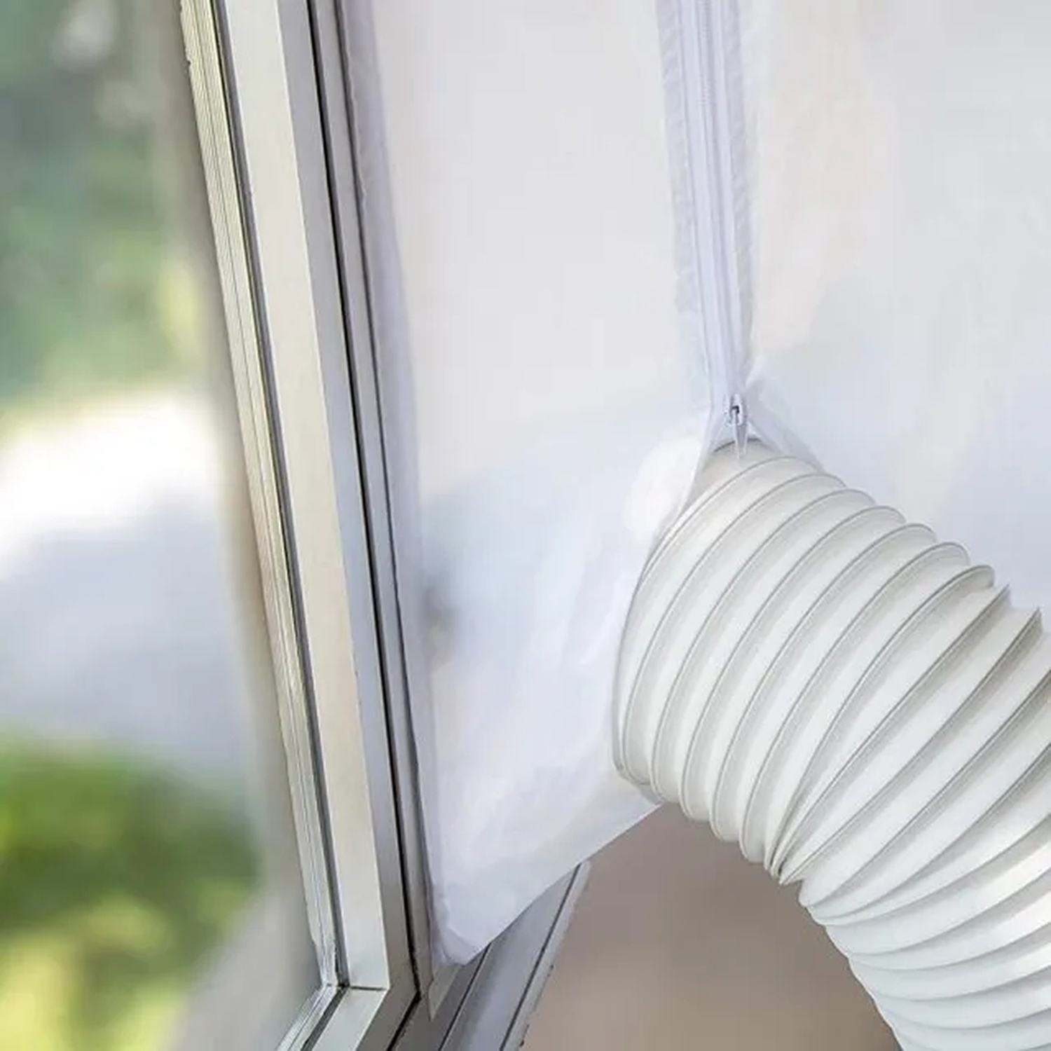 Een wit raam met vrij uitzicht. Een witte airconditioningslang is met een rits aan het raam bevestigd.