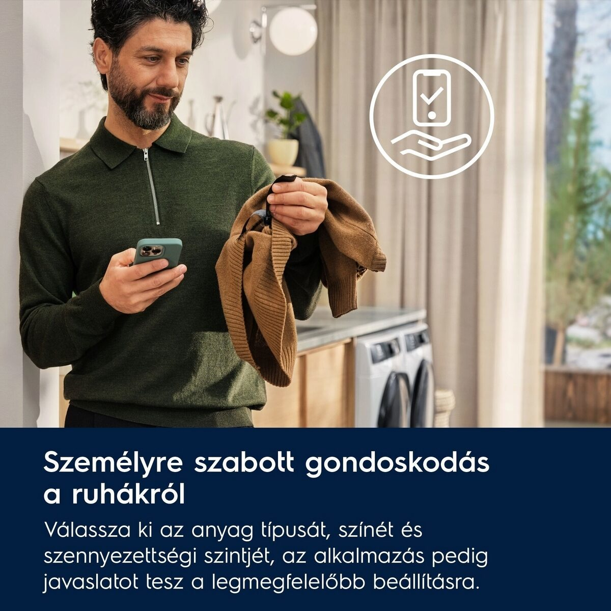 Férfi telefont és barna pulóvert tart. Mosógép a háttérben. Szöveg: Személyre szabott gondoskodás a ruhákról.