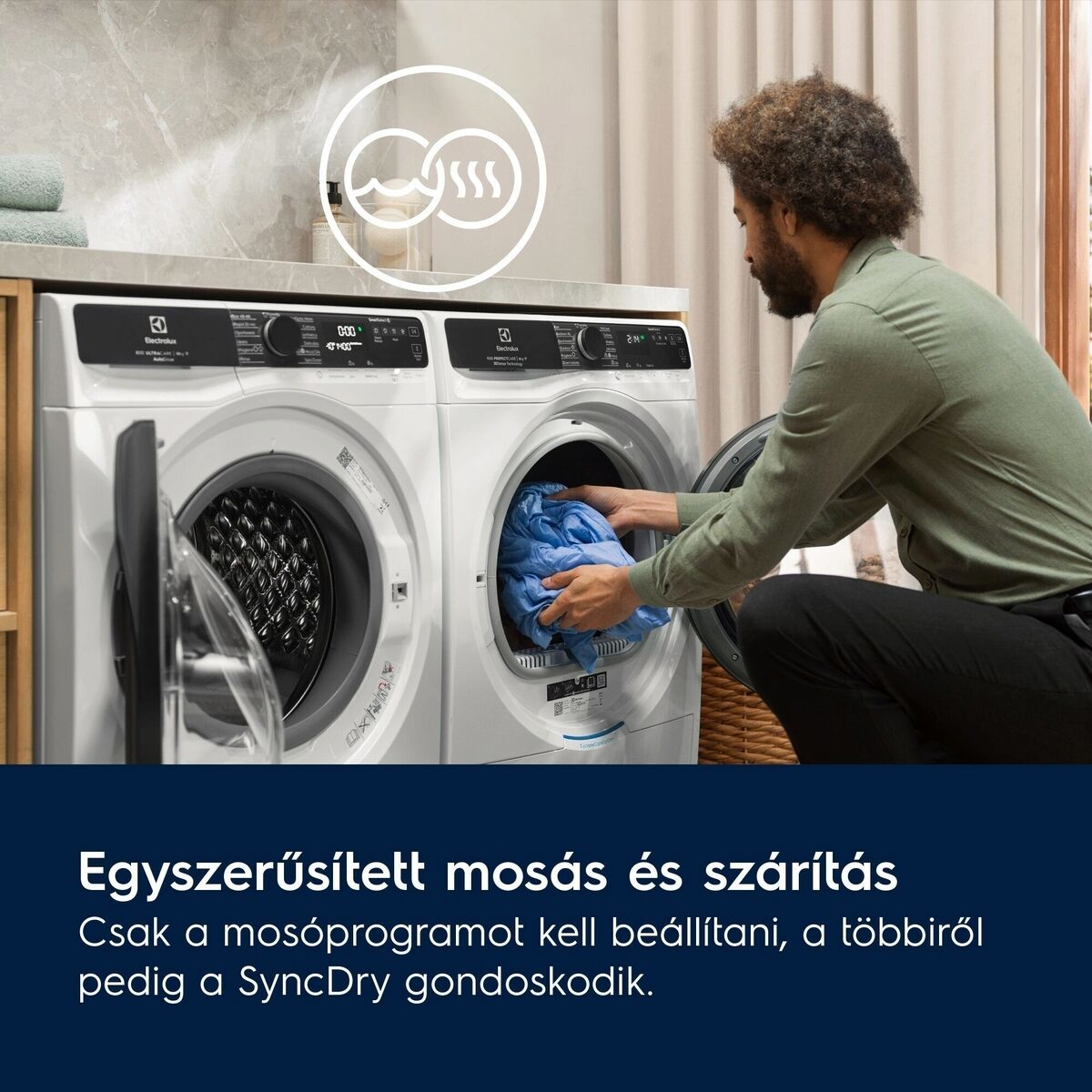 Férfi kék ruhát tölt fehér mosógépbe. Egy másik gép mellette. Gőz logó a háttérben.