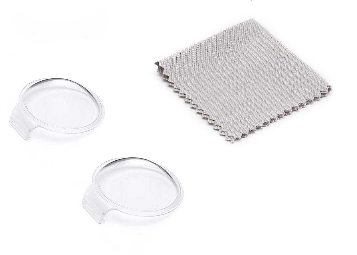 Dwie przezroczyste, okrągłe osłony obiektywu i szara ściereczka z mikrofibry na białym tle.