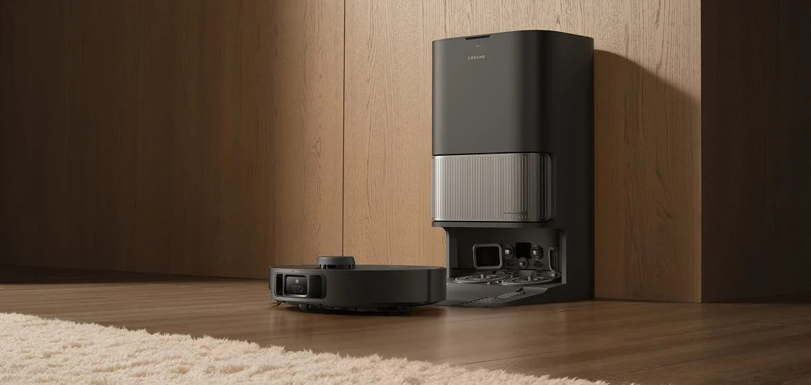 Czarny robot odkurzający i stacja ładująca stoją na drewnianej podłodze. Puszysty dywan jest na pierwszym planie.