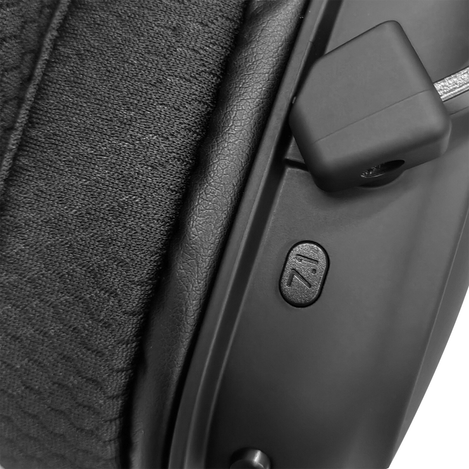 Zbliżenie czarnych słuchawek. Widoczna poduszka na uszy, przycisk 7.1 i złącze. Szczegóły obejmują tekstury i kształty.