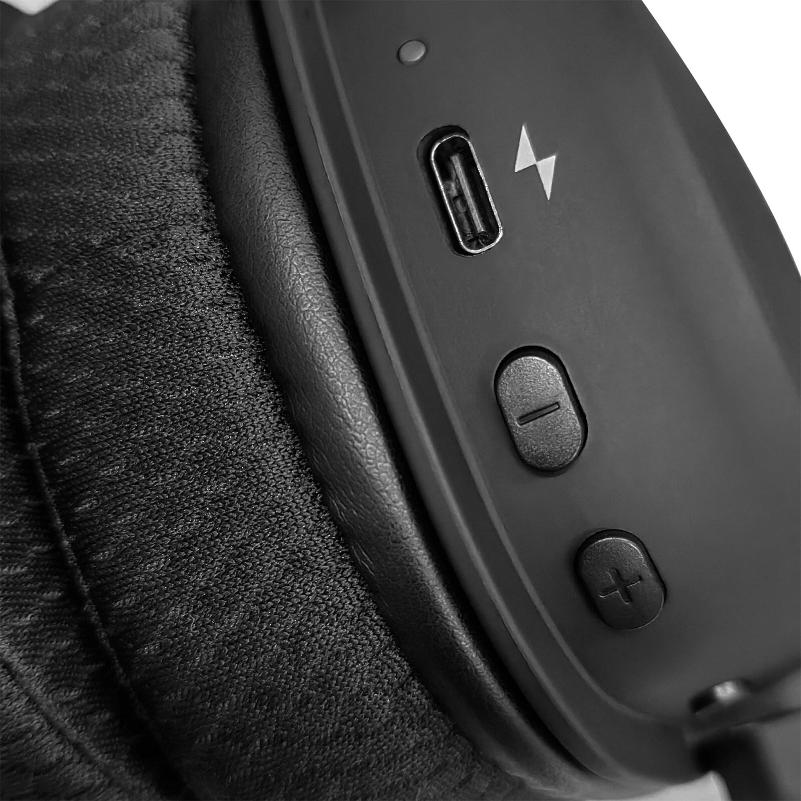 Zbliżenie czarnych słuchawek. Widoczne nauszniki, przyciski, port USB-C i symbol ładowania.