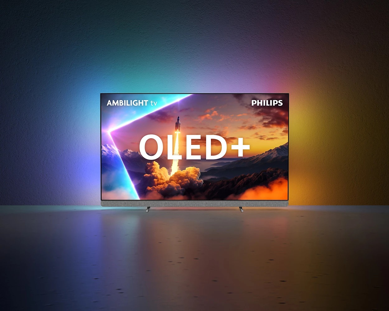 Telewizor Philips OLED+ wyświetla startującą rakietę nad górami. Ekran jest podświetlony żywymi kolorami, z białym napisem 'OLED+'.