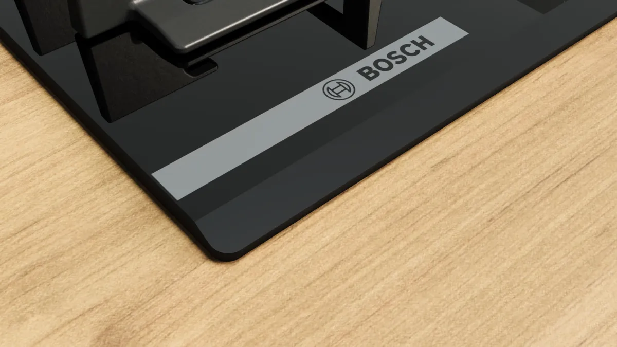 Açık renk ahşap yüzey üzerinde siyah bir Bosch cihazı. Bosch logosu görünür. Cihaz şık ve modern bir tasarıma sahip.