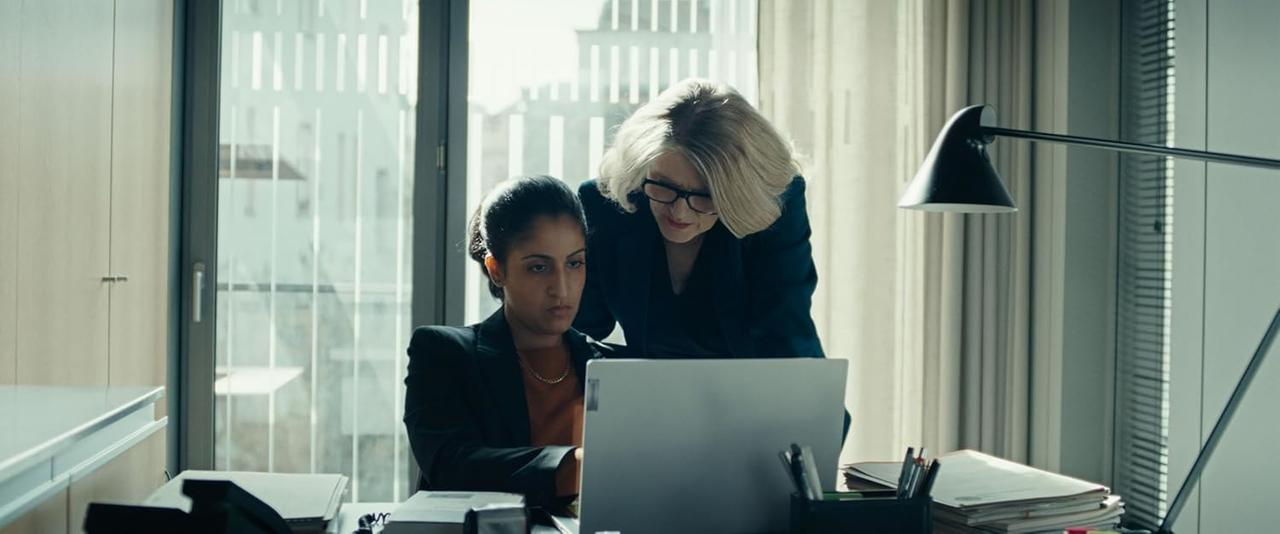 Zwei Frauen blicken auf einen Laptop in einem Büro.