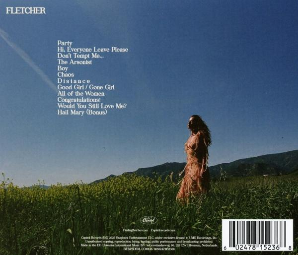Eine Frau in einem Kleid steht in einem Feld mit hohem Gras. Berge sind im Hintergrund. Der Himmel ist blau mit Text links.