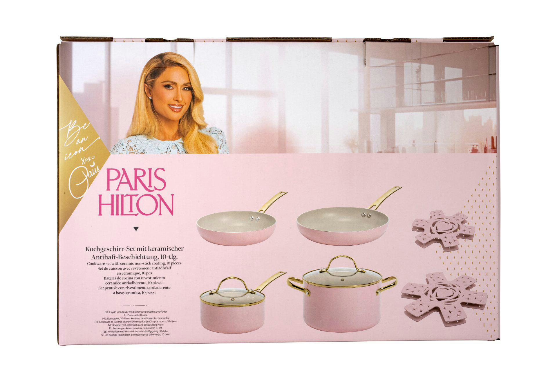 Karton mit Paris Hilton, rosa Kochgeschirr und Untersetzern. Text in mehreren Sprachen beschreibt das Produkt.