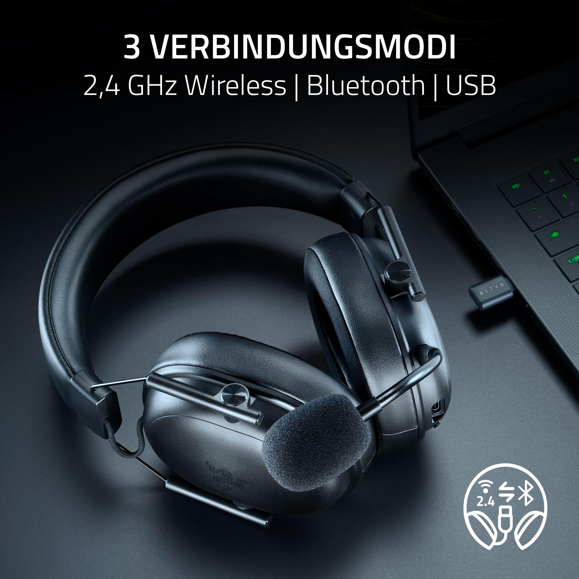 Schwarzes Headset mit Mikrofon, USB-Dongle und Laptop auf dunkler Oberfläche. 2,4 GHz Wireless, Bluetooth und USB.