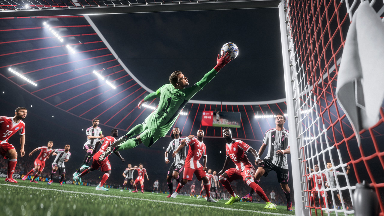 Un gardien de but en vert plonge pour attraper un ballon de football dans un stade. D'autres joueurs en rouge et blanc sont en arrière-plan.