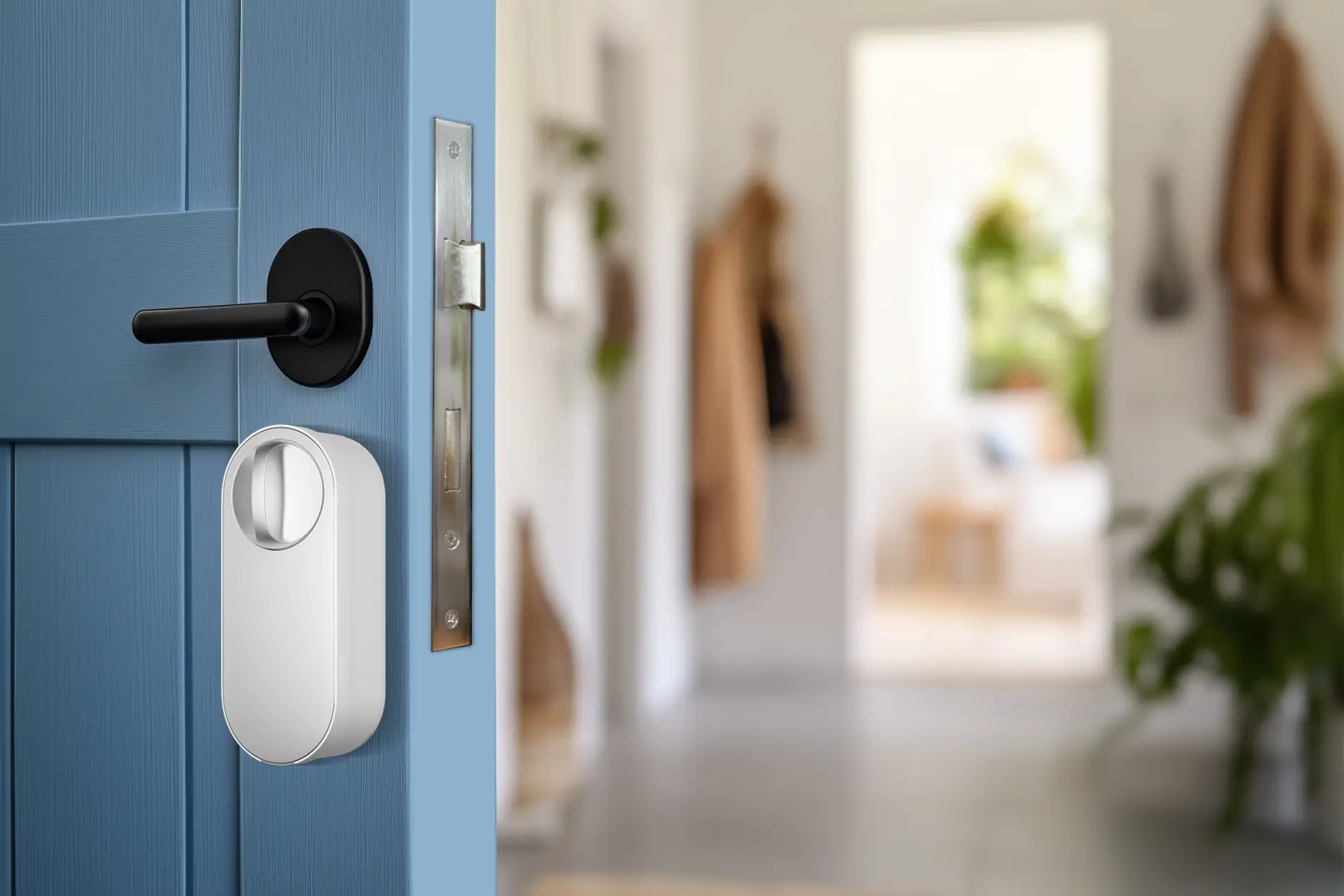 Blaue Tür mit schwarzem Griff, weißem Smart Lock und silbernem Riegel. Flur im Hintergrund, unscharf. Mäntel hängen.