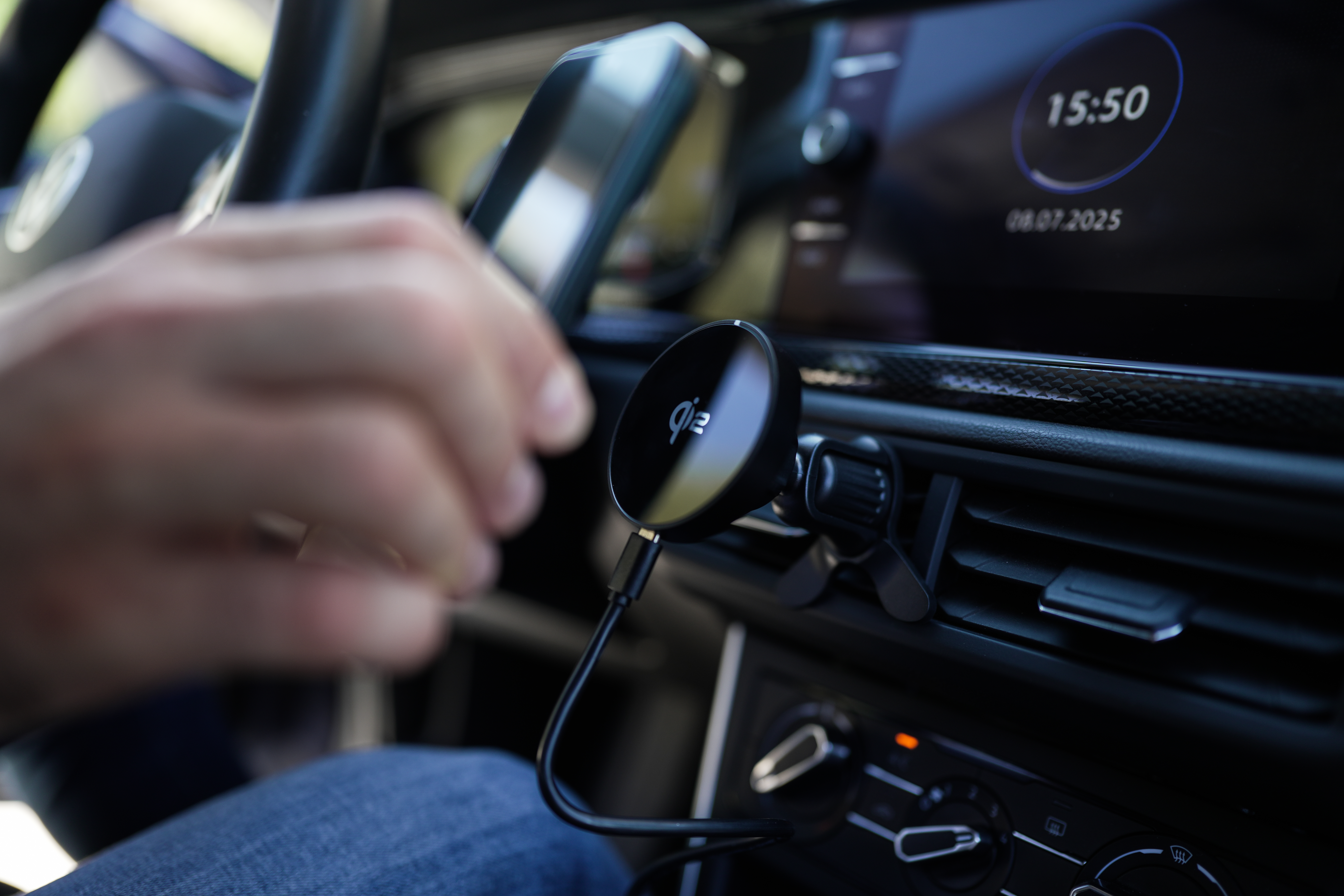 Autointerieur mit kabellosem Ladepad, Hand und Display mit Uhrzeit und Datum.