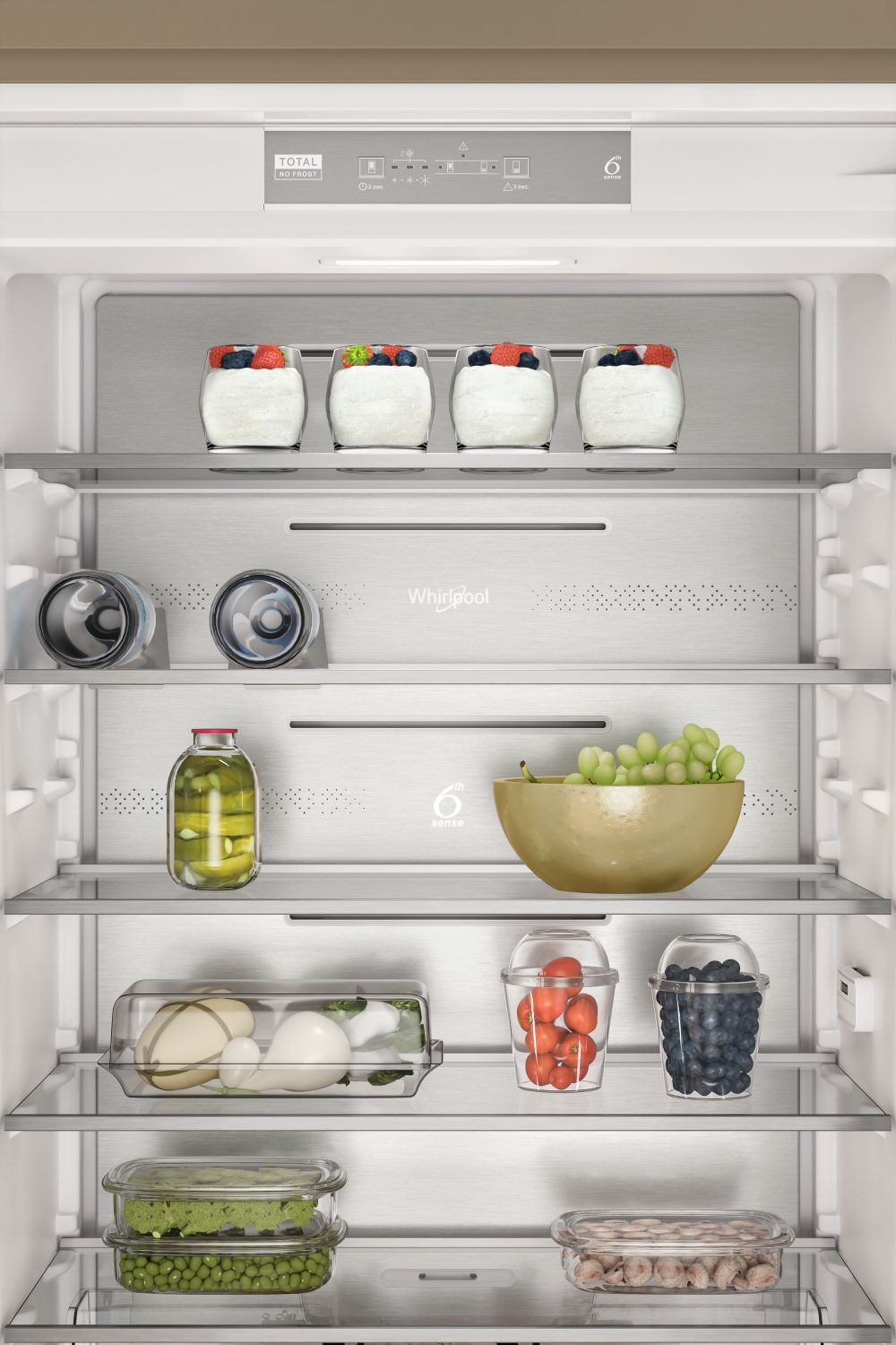 Interior de nevera con alimentos. Yogur con bayas, bebidas, encurtidos, uvas y otros recipientes. Todo en estantes de vidrio.