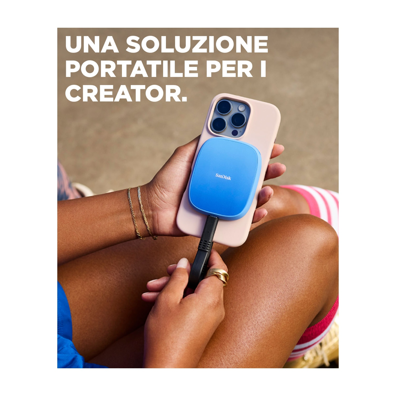 Persona che tiene in mano un telefono con un dispositivo Sandisk blu collegato. Il testo recita: Una soluzione portatile per i creatori.