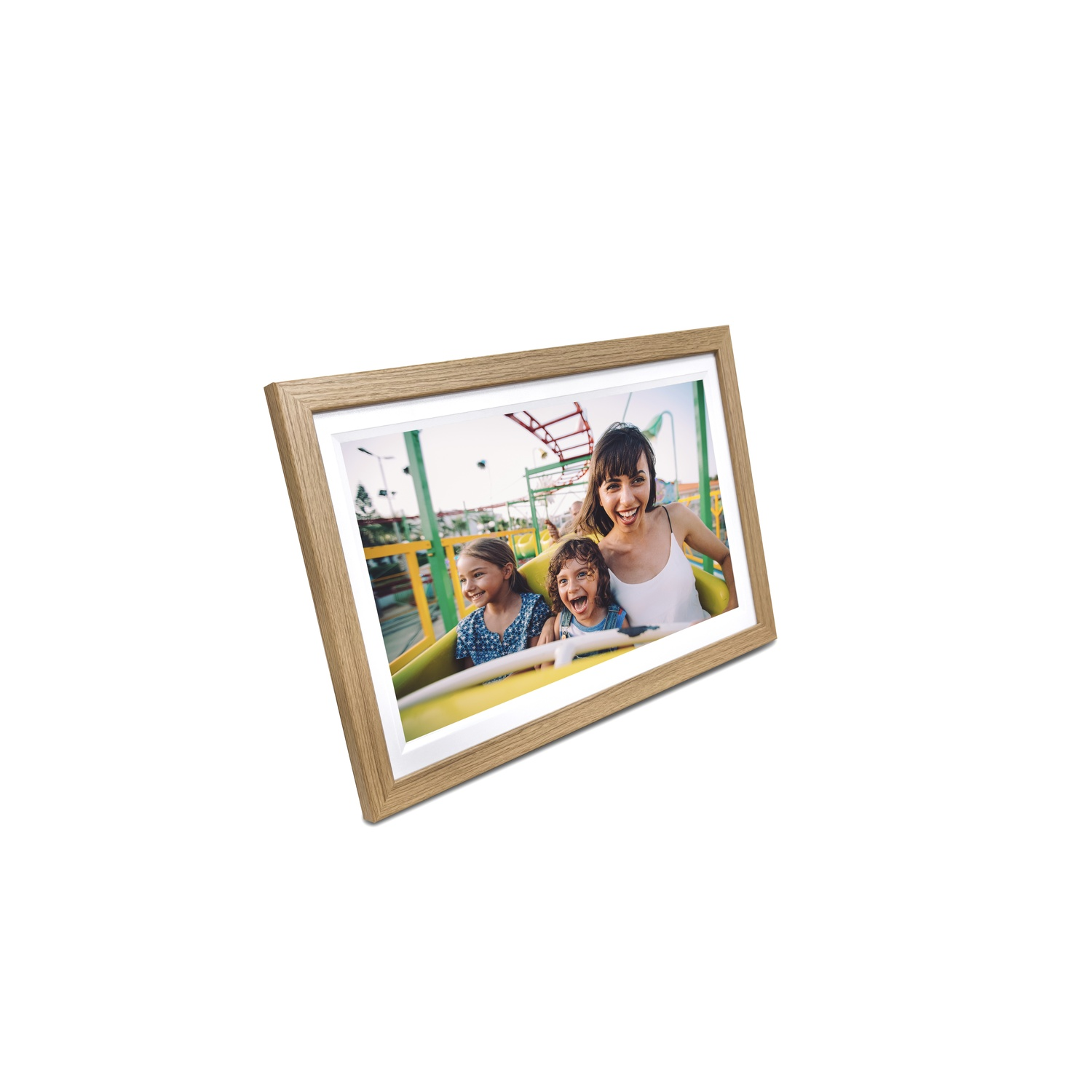 Une image encadrée montre une femme et deux enfants sur un manège, tous souriants. Le cadre est en bois, sur fond blanc.