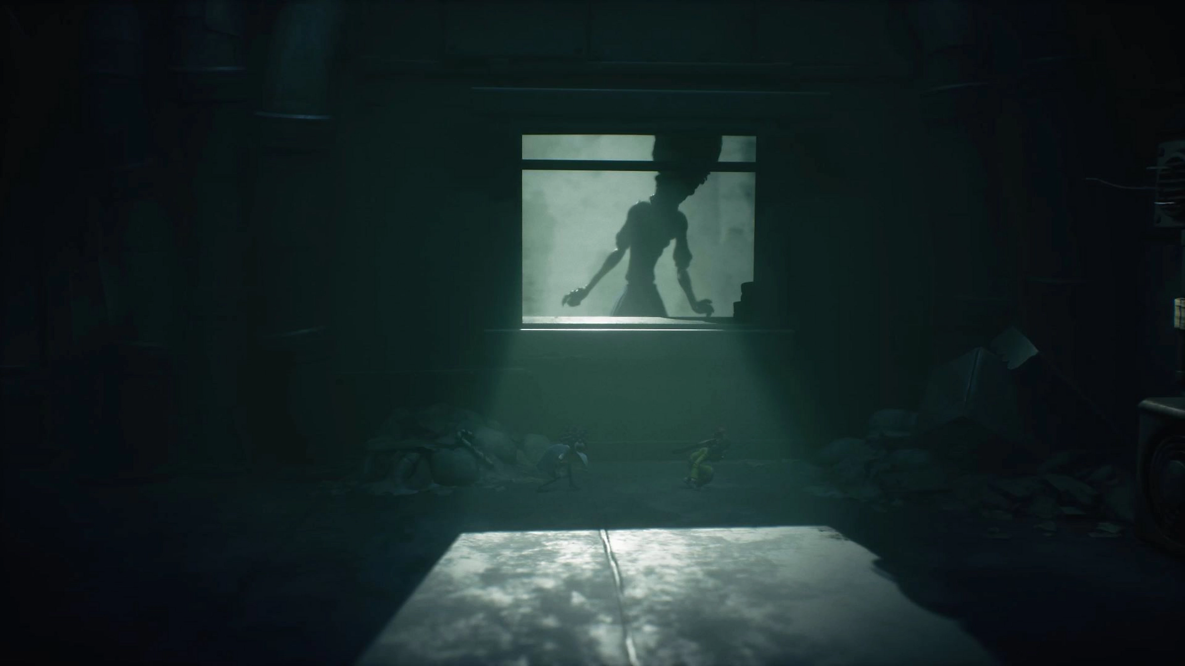 Stanza scarsamente illuminata. Figura alla finestra. Due piccole figure in primo piano, illuminate da un raggio di luce.