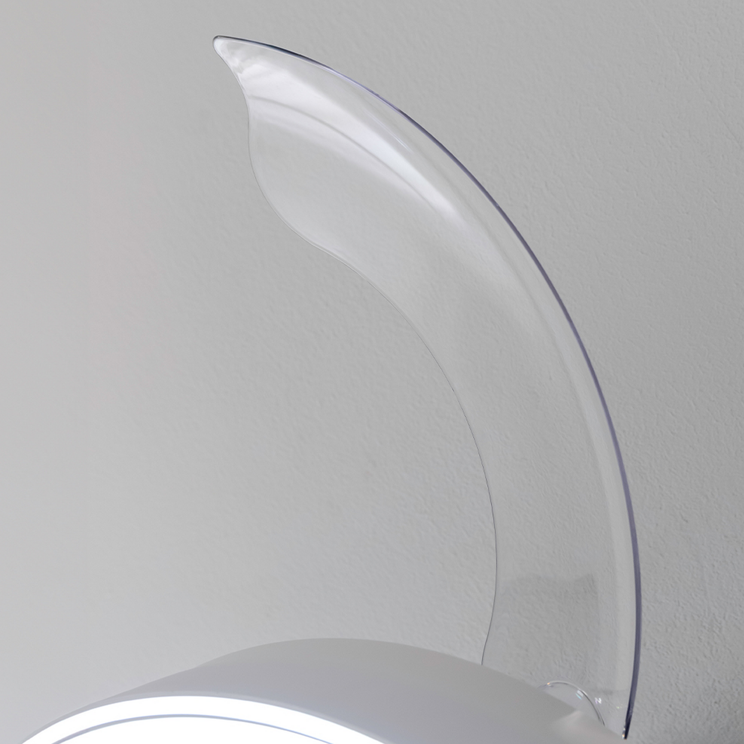 Primer plano de una aspa de ventilador de techo blanca con borde transparente y curvado sobre fondo gris.