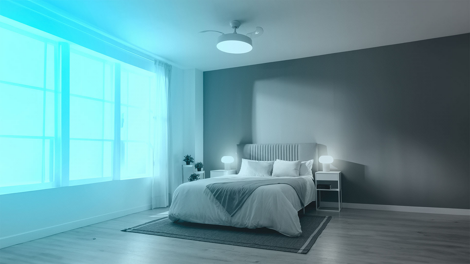 Dormitorio con cama, ventana grande, ropa de cama blanca, pared gris, ventilador de techo y dos mesitas de noche con lámparas.